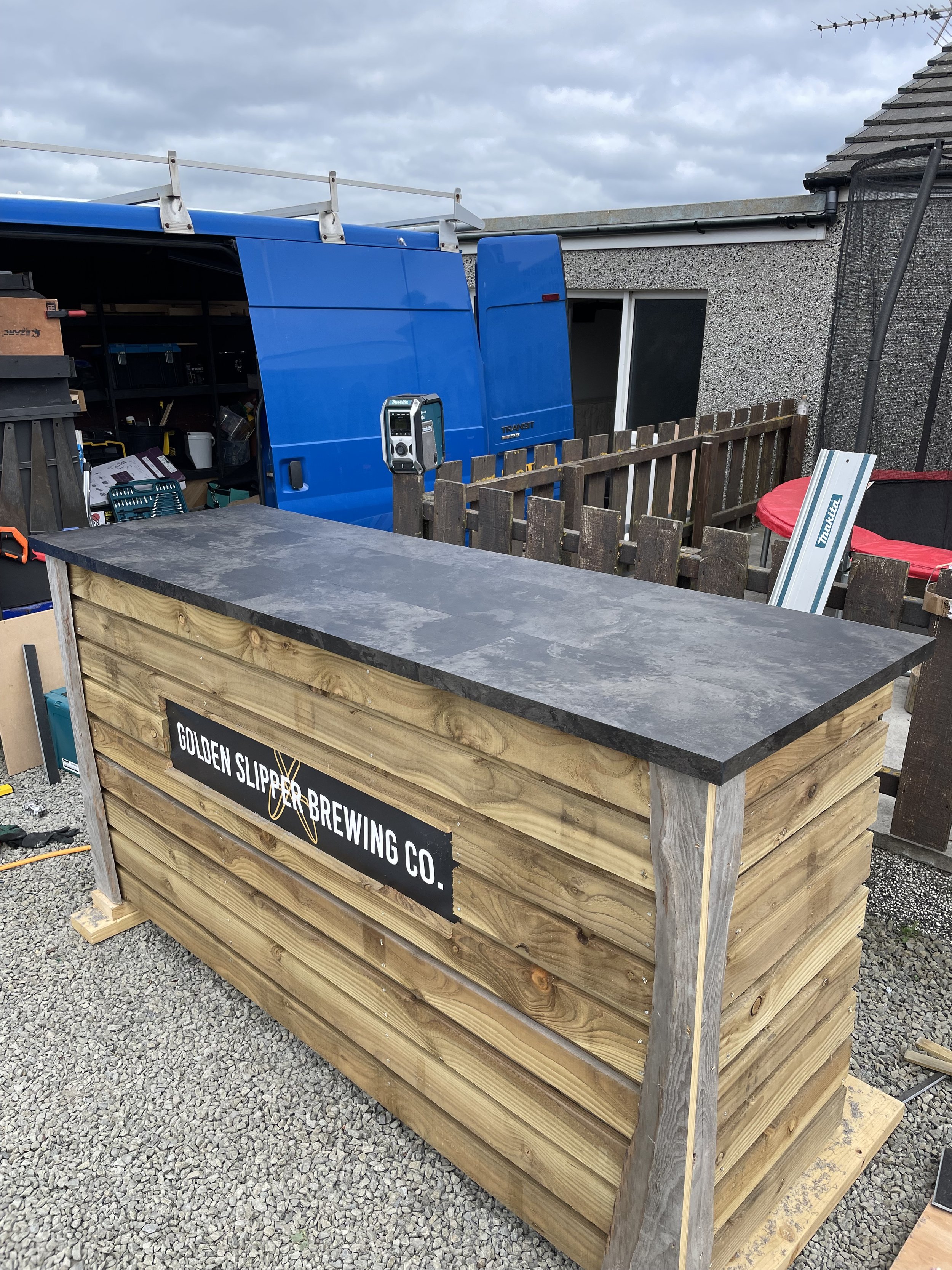 A wooden bar with a dark gray countertop outside.