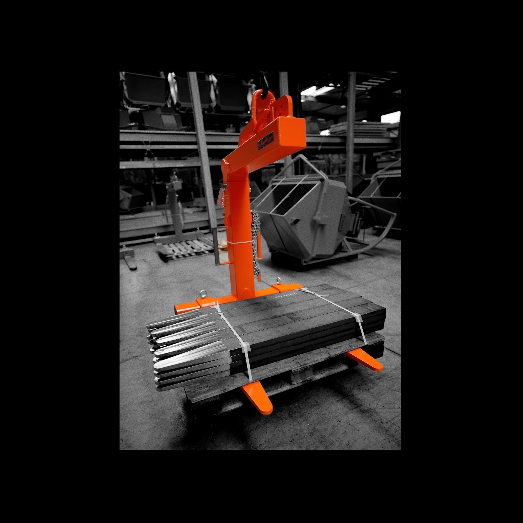 Crane Pallet forks lifting a load at the factory. The photo of the forks is orange with a black and white background.