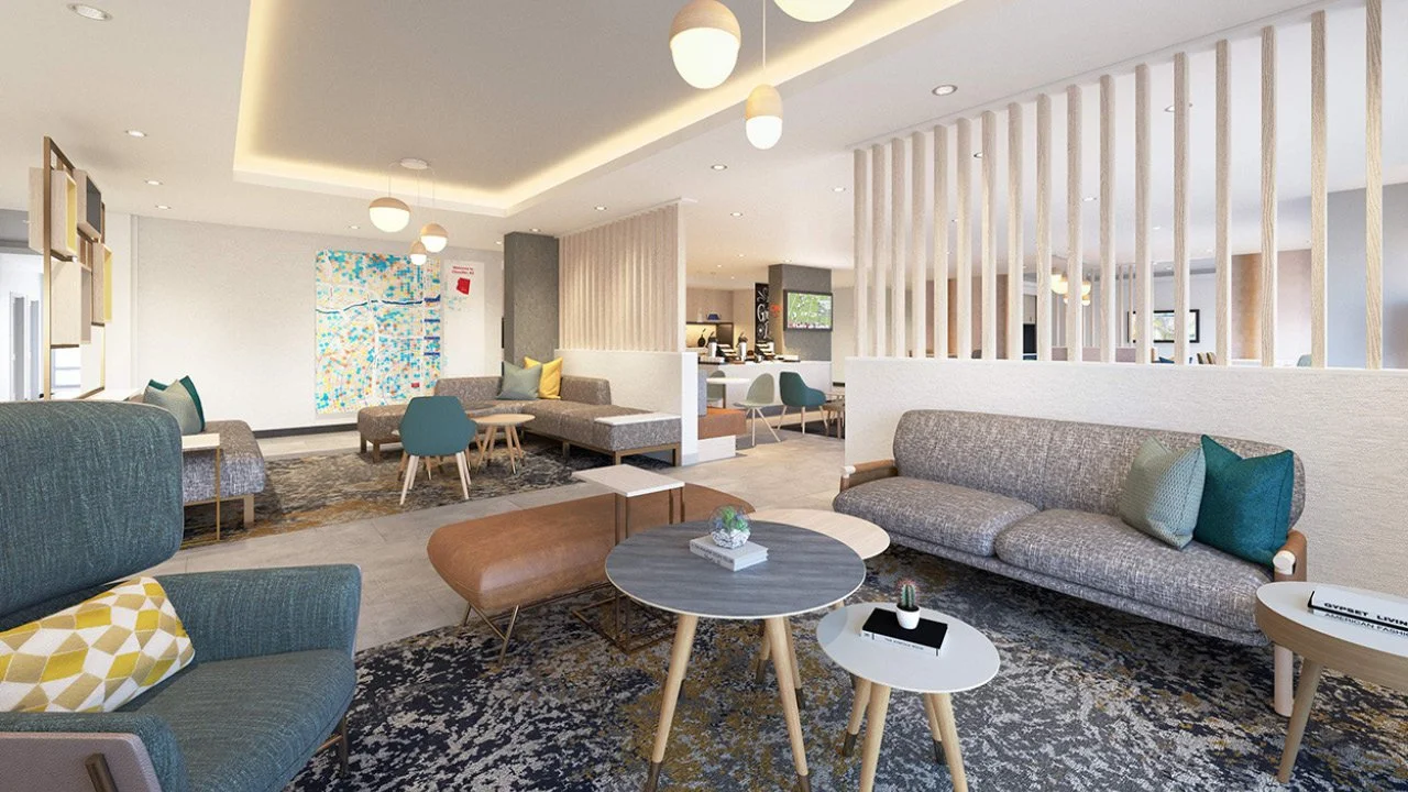 Modern hotel lobby for Towneplace Suites by Marriott with sofas, coffee tables, and decorative pillows, featuring neutral and pastel colors and contemporary lighting fixtures.