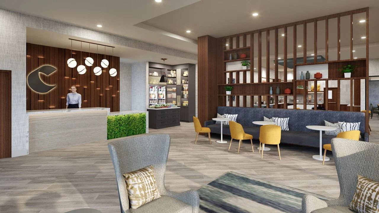Modern prototype hotel lobby for Comfort by Choice Hotels, with a front desk, lounge area with yellow and gray chairs, a black couch with pillows, and a decorative wooden partition. Background shows a snack and beverage station.