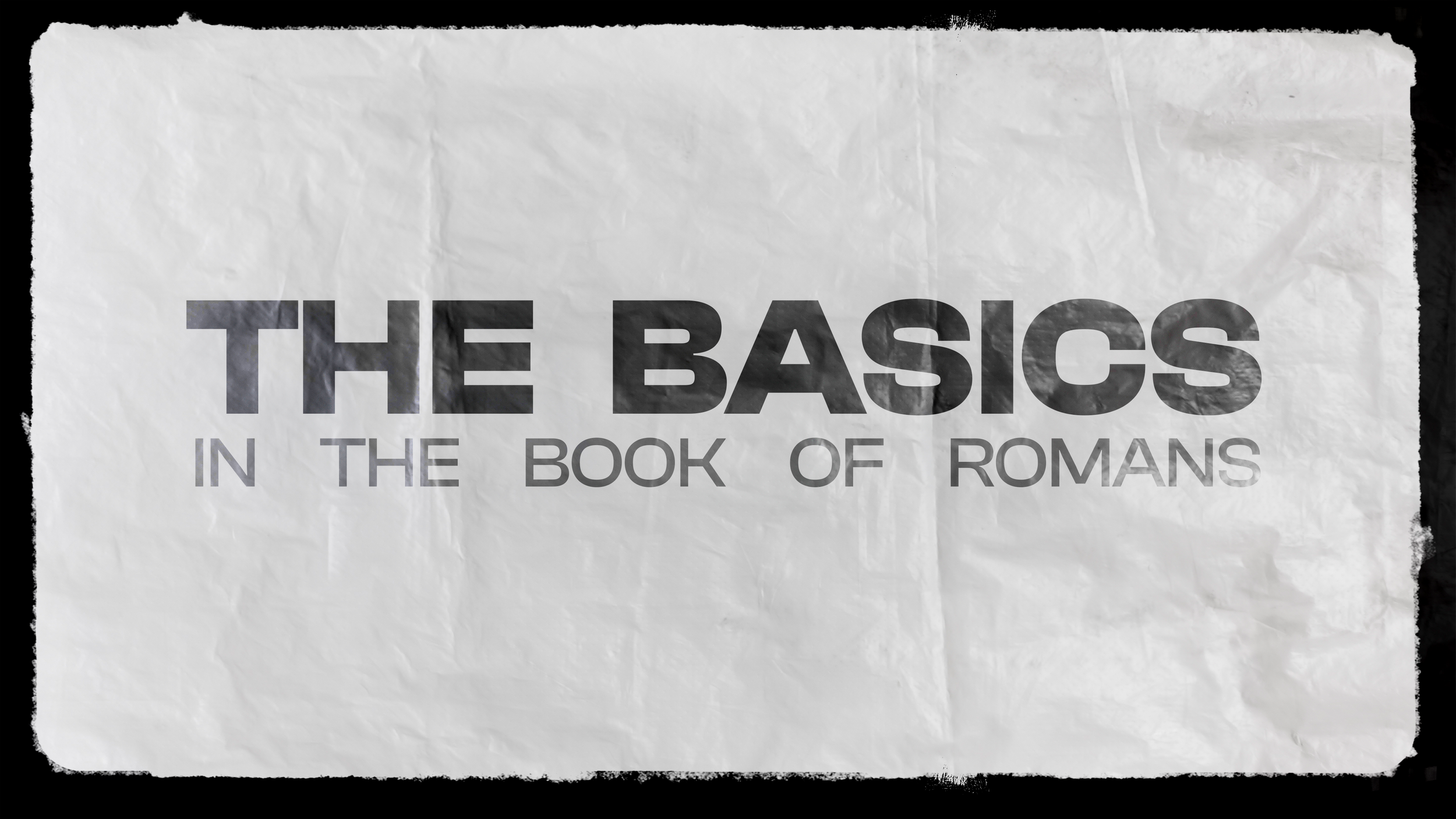 Text on a crumpled white paper that says 'The Basics in the Book of Romans' in bold black and gray font.