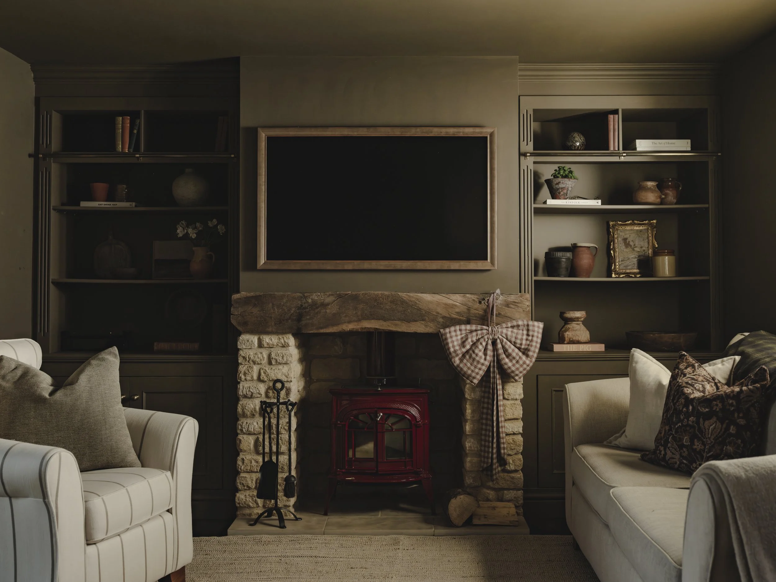 Living room with a fireplace, blackboard above it, built-in shelves with decorative items, and two sofas.