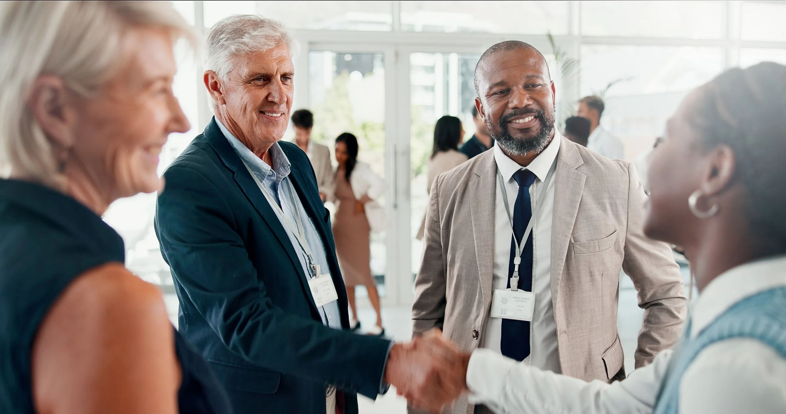 Group of diverse business professionals at a conference, exchanging greetings and handshakes.