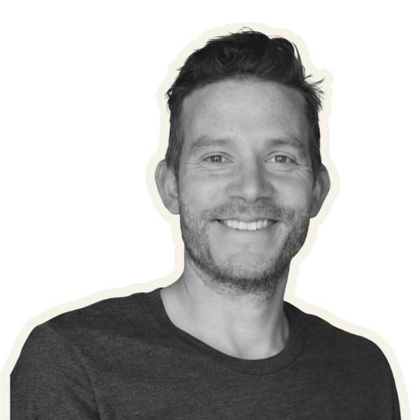 Black and white portrait of a young man with short hair and a beard, wearing a jacket and carrying a backpack.