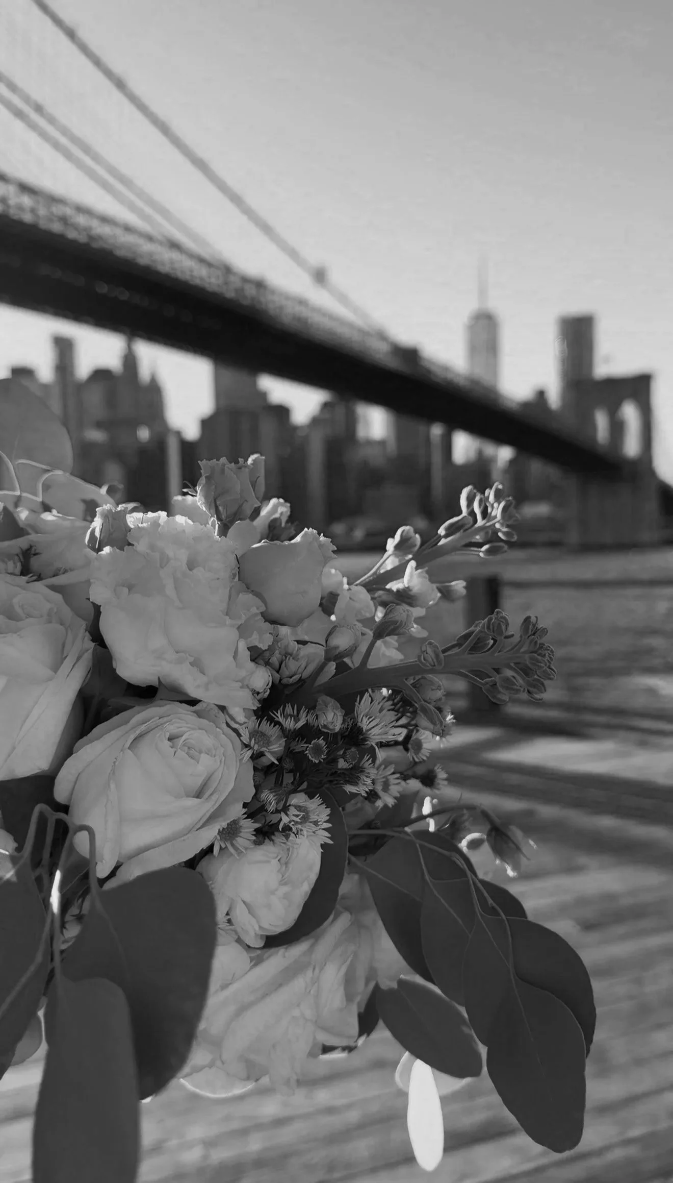 A bouquet of flowers with the Brooklyn Bridge and the New York City skyline in the background.