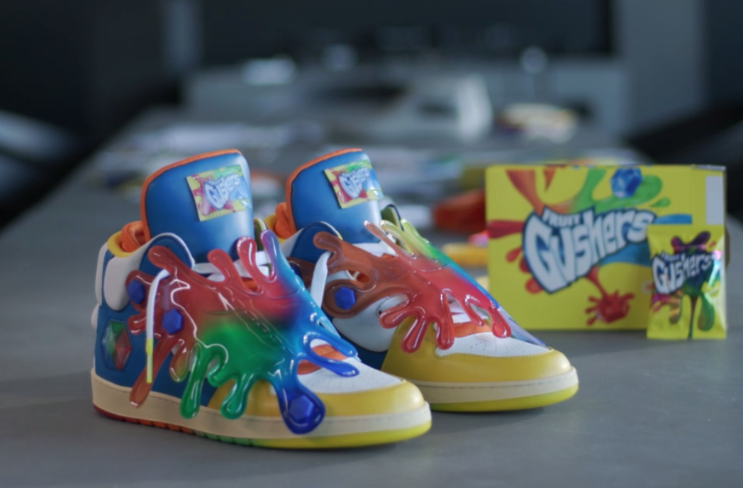 Colorful sneakers with splash paint design next to a box of fruit Gushers candy.