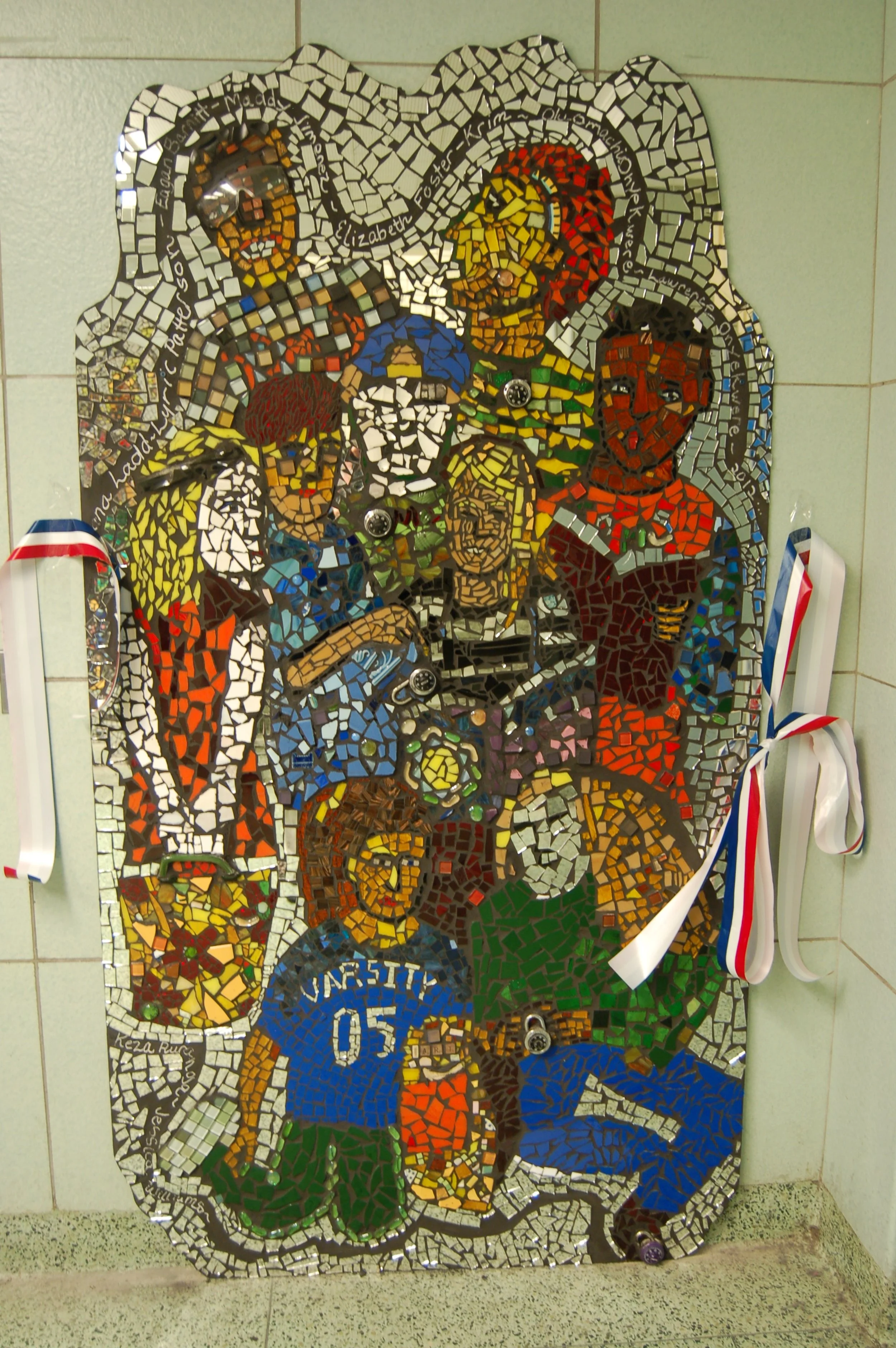 A mosaic artwork of a family portrait with eight people, including children and adults, assembled with small colorful tiles, decorated with medals and ribbons attached to its side.