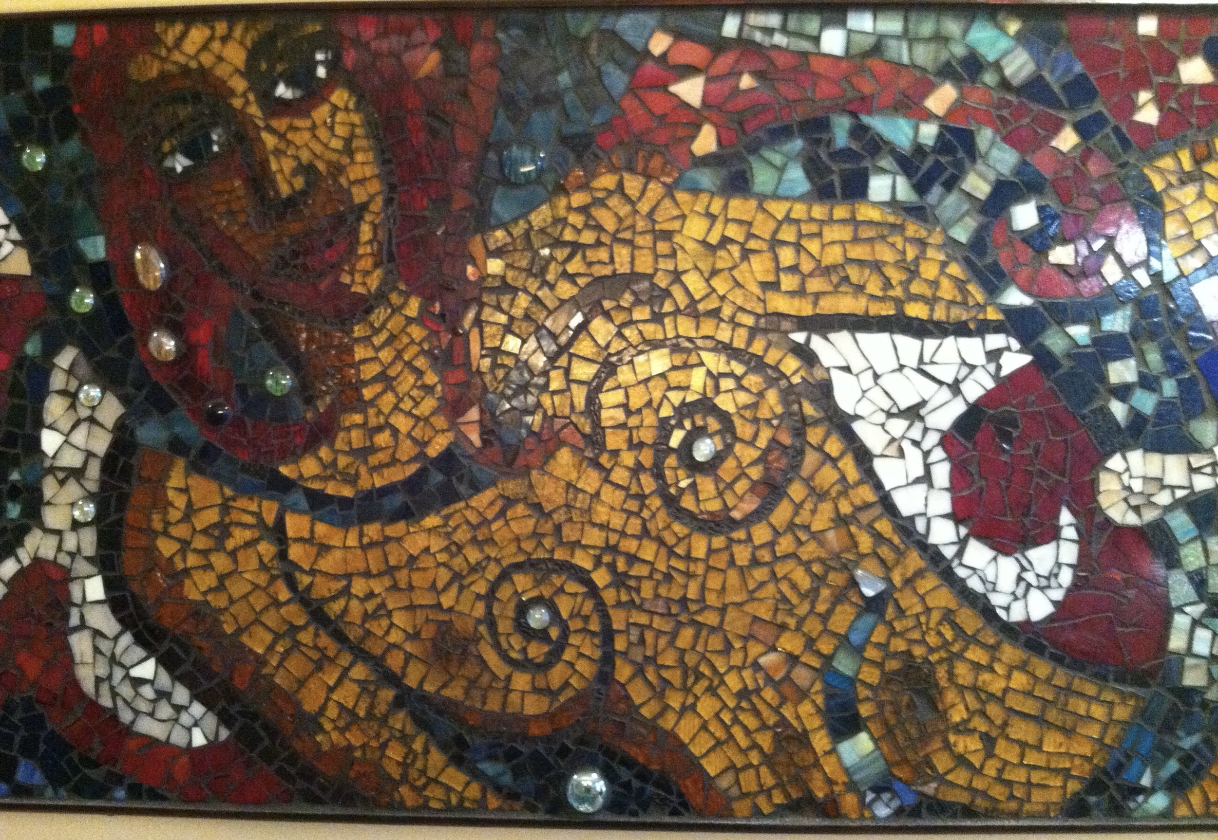 A colorful mosaic artwork depicting a woman with long hair and a pig, using small tiles in various colors.