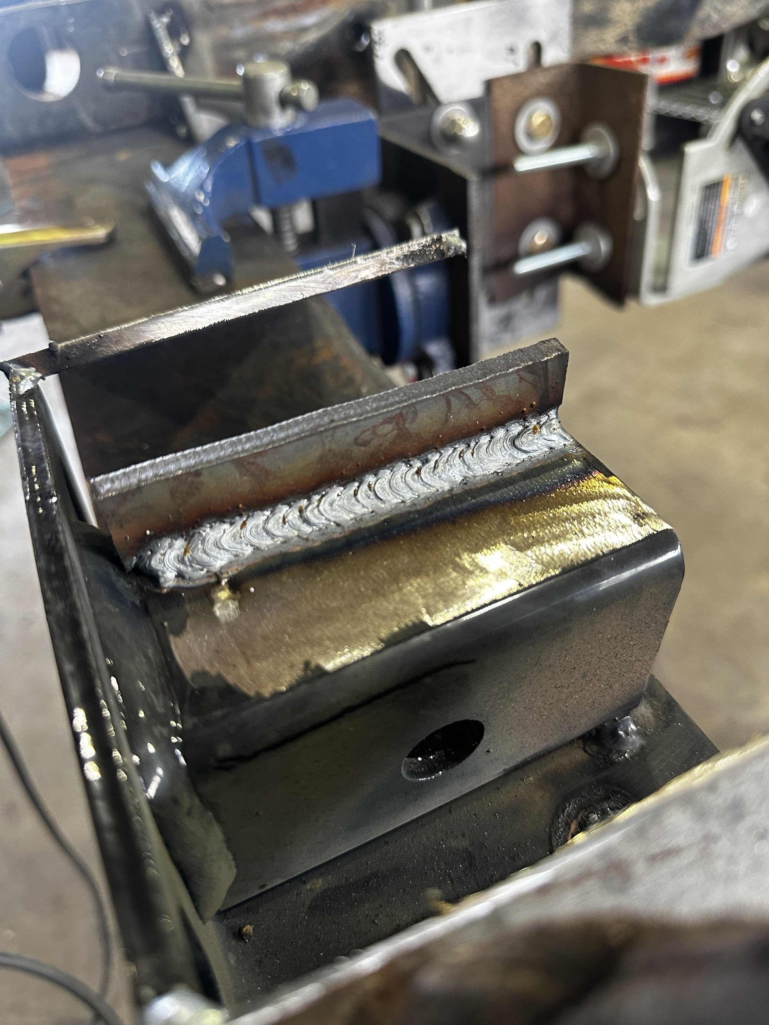 Close-up of a metal welding repair inside a metal box or frame, with visible weld beads on the seams.