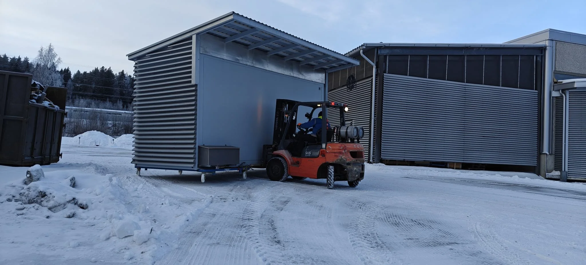 Trukilla siirtämässä suurta metallista rakennetta lumisella tiellä.