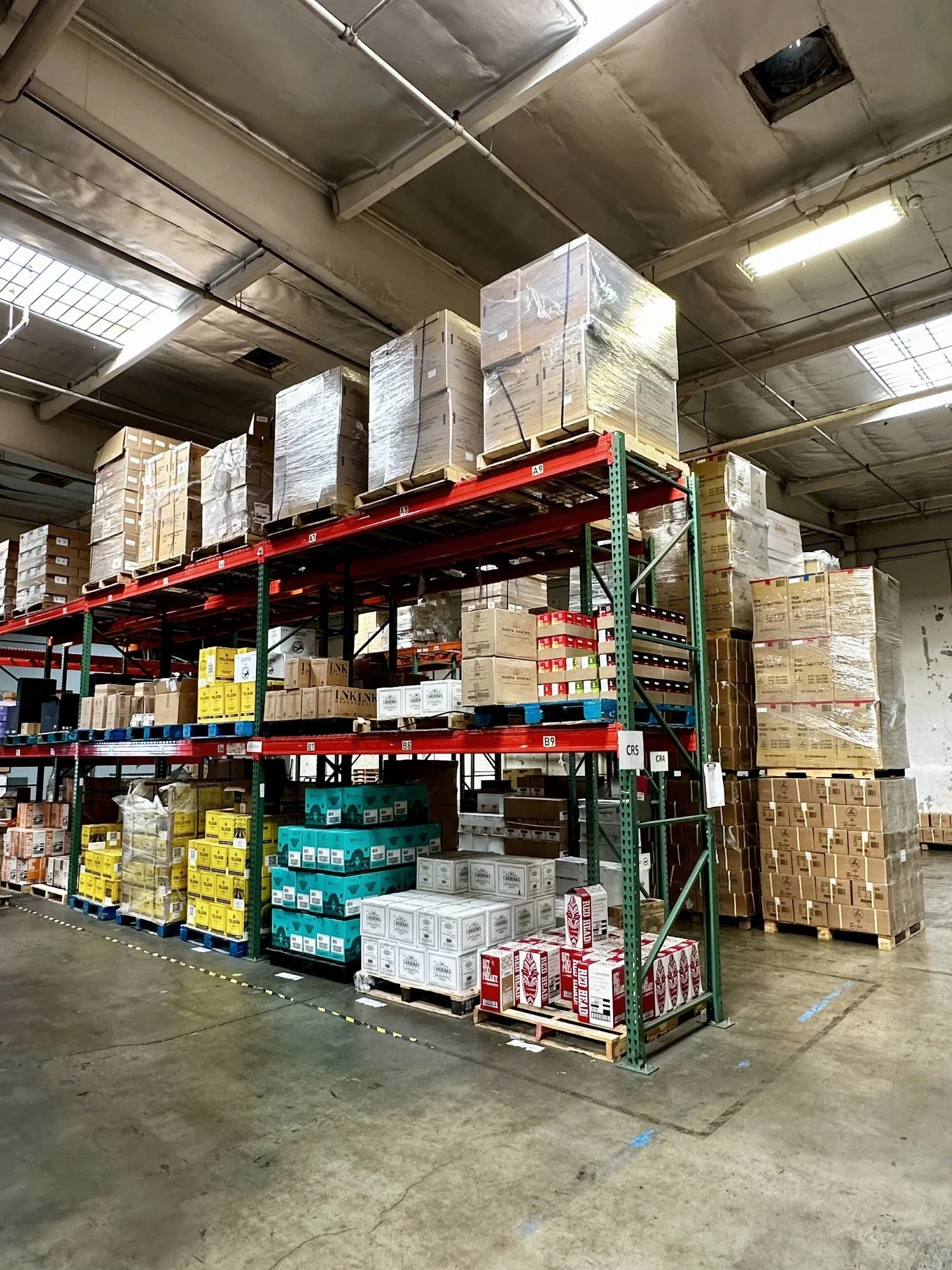 Interior of a warehouse with shelves filled with boxes and pallets of various goods.