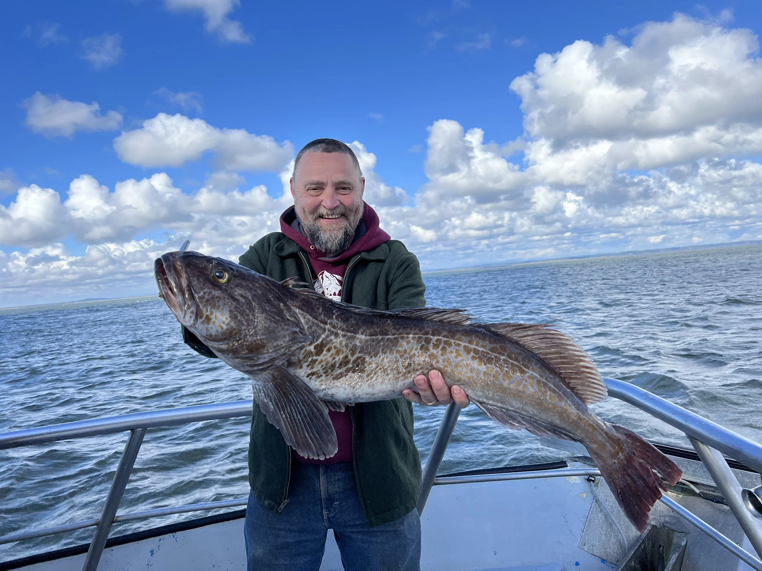 Man smiling holding a lingcod on a fishing charter in Westport, wa on the tequila too