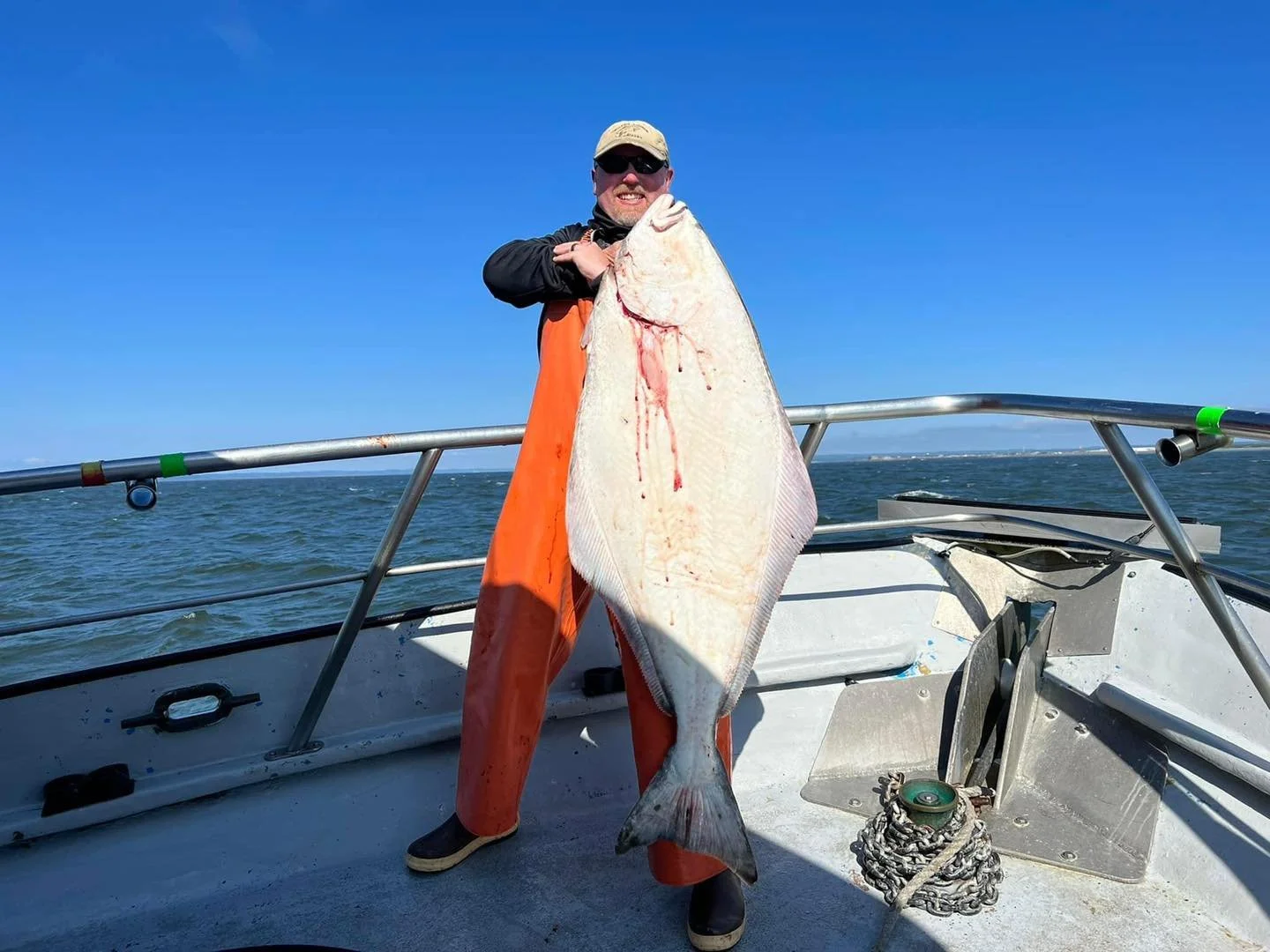 Customer on tequila too holding a large halibut caught on a fishing charter in Westport, wa