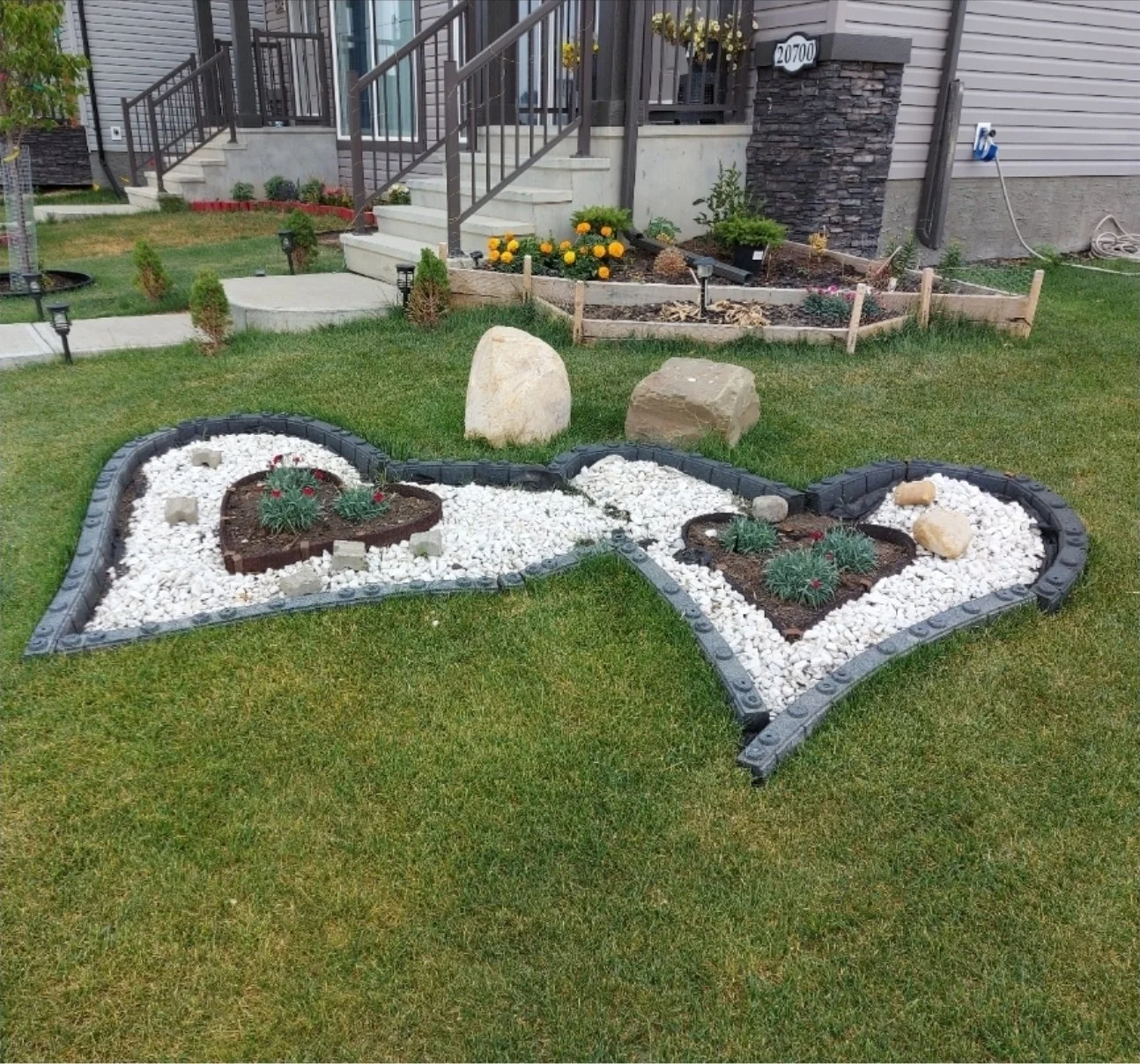 Decorative white-rock garden beds with stone edging and boulders in an Edmonton front yard