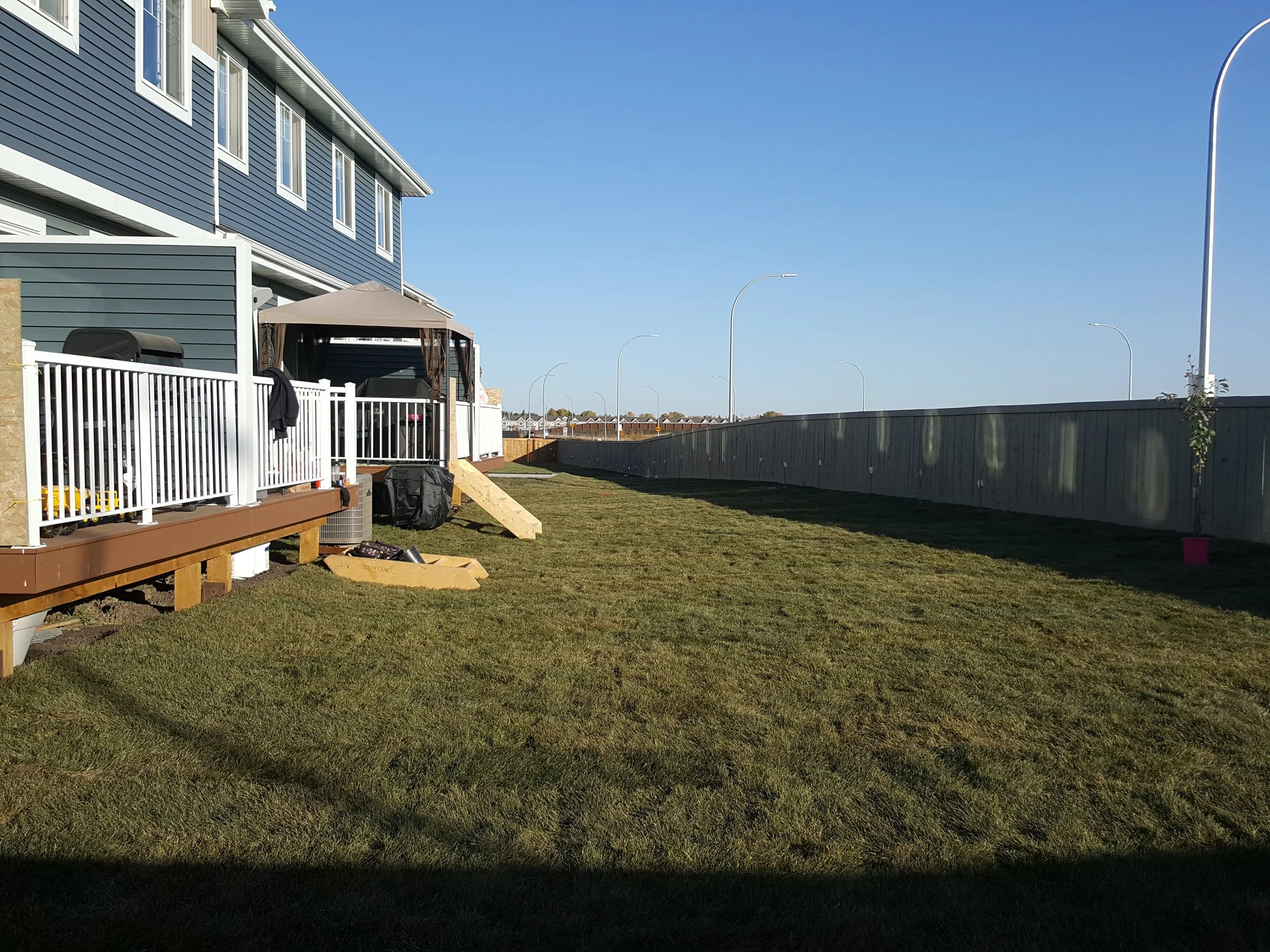 Freshly laid sod in a new-build Edmonton backyard beside a wooden deck