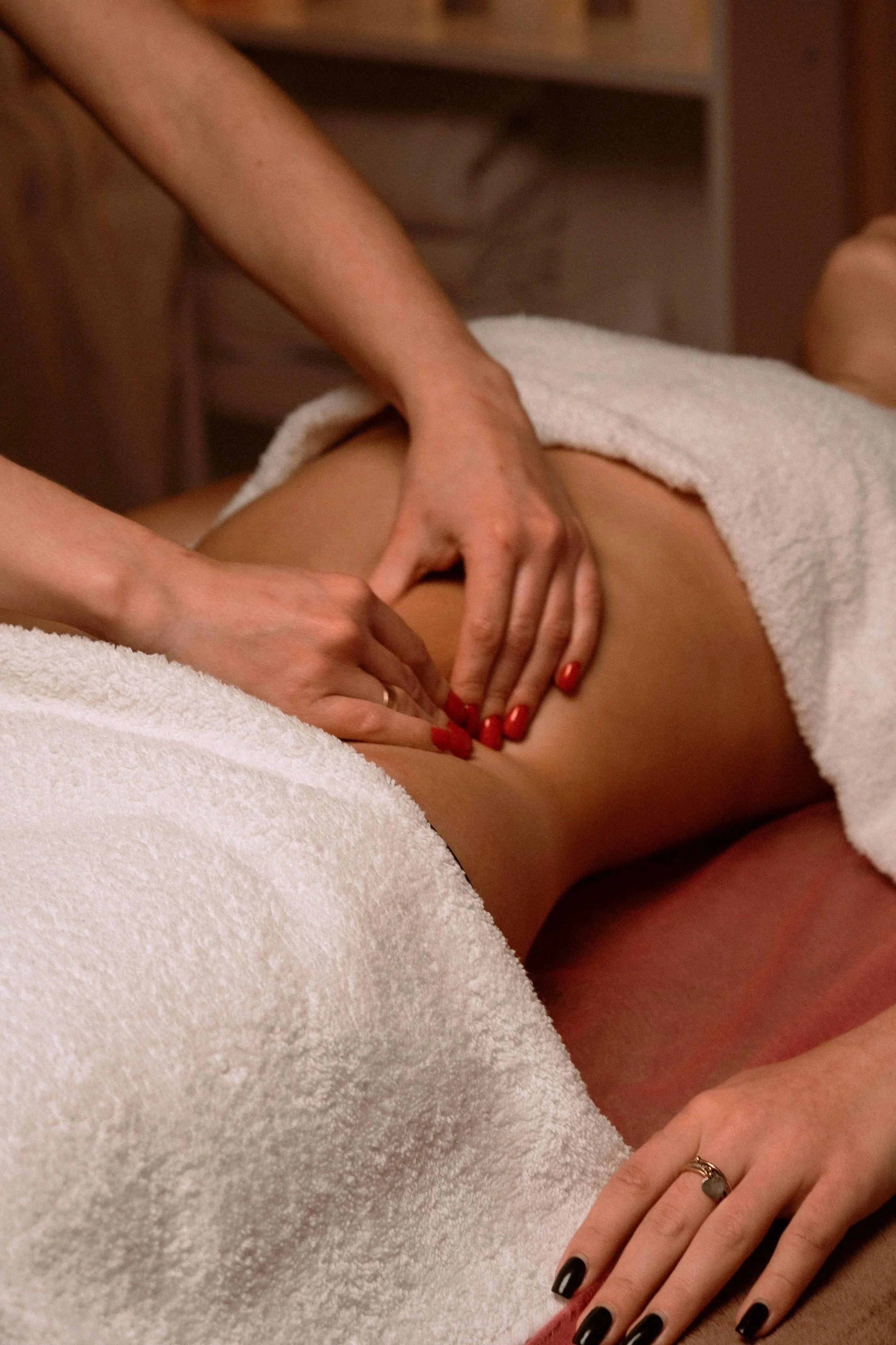 A person receiving a massage on their back with a towel covering the lower body.