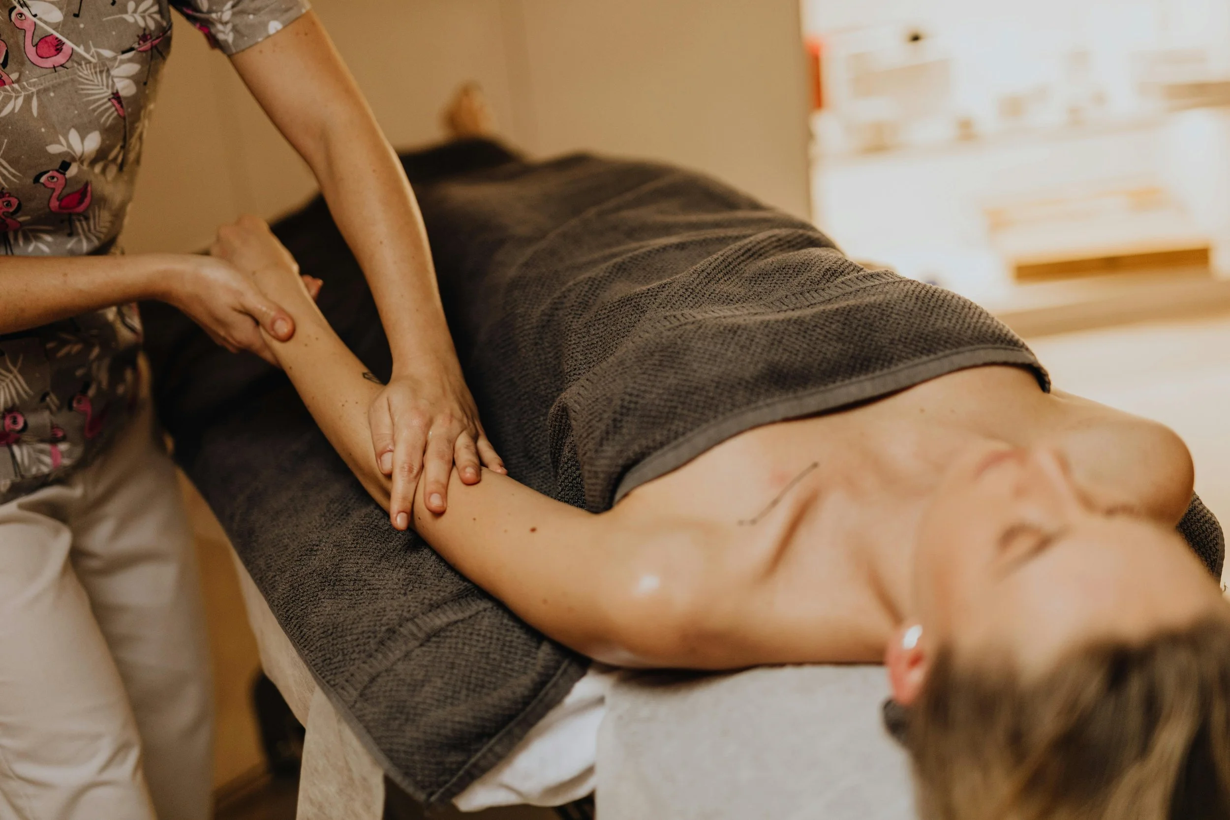 A woman receiving a massage from a massage therapist in a spa or wellness setting.