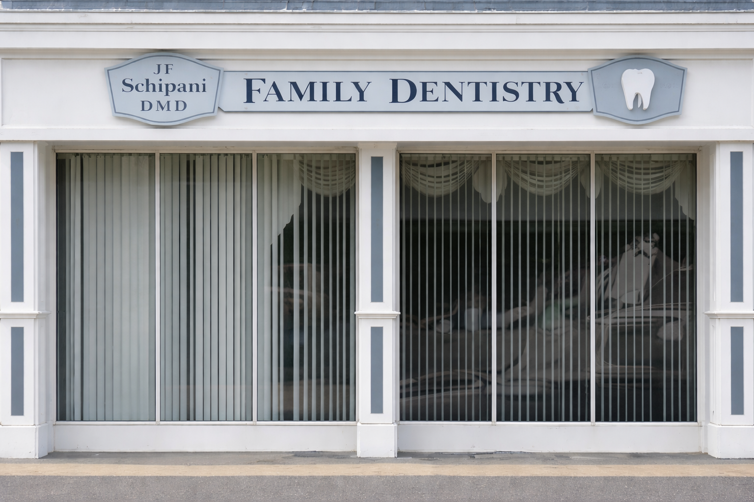 Exterior of a family dentistry office with large glass windows covered by vertical blinds, blue and white signage with a tooth logo and the words 'Family Dentistry'.