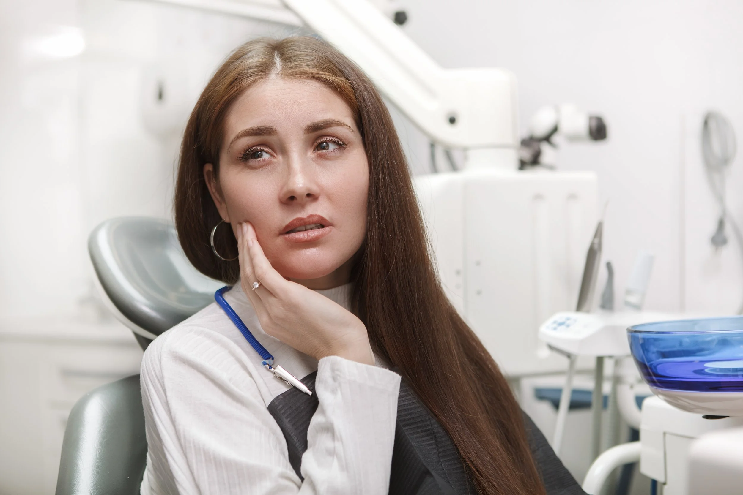 Woman at a dental clinic, sitting in the chair with dental equipment in background.