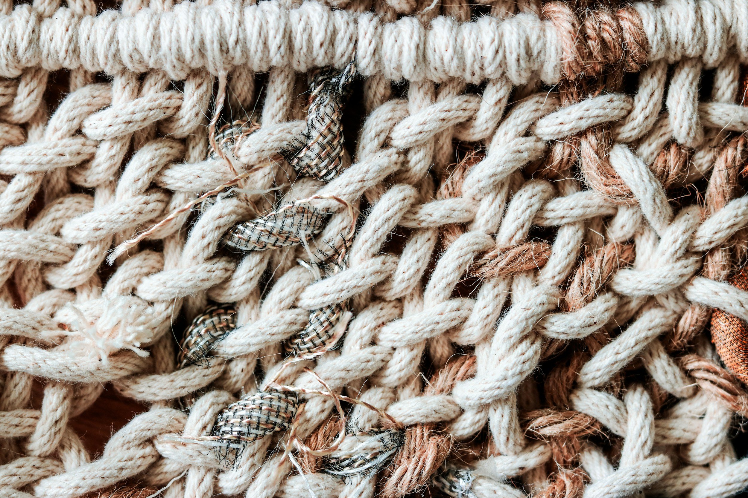 Close-up of tangled various beige, brown, and multicolored ropes and strings.