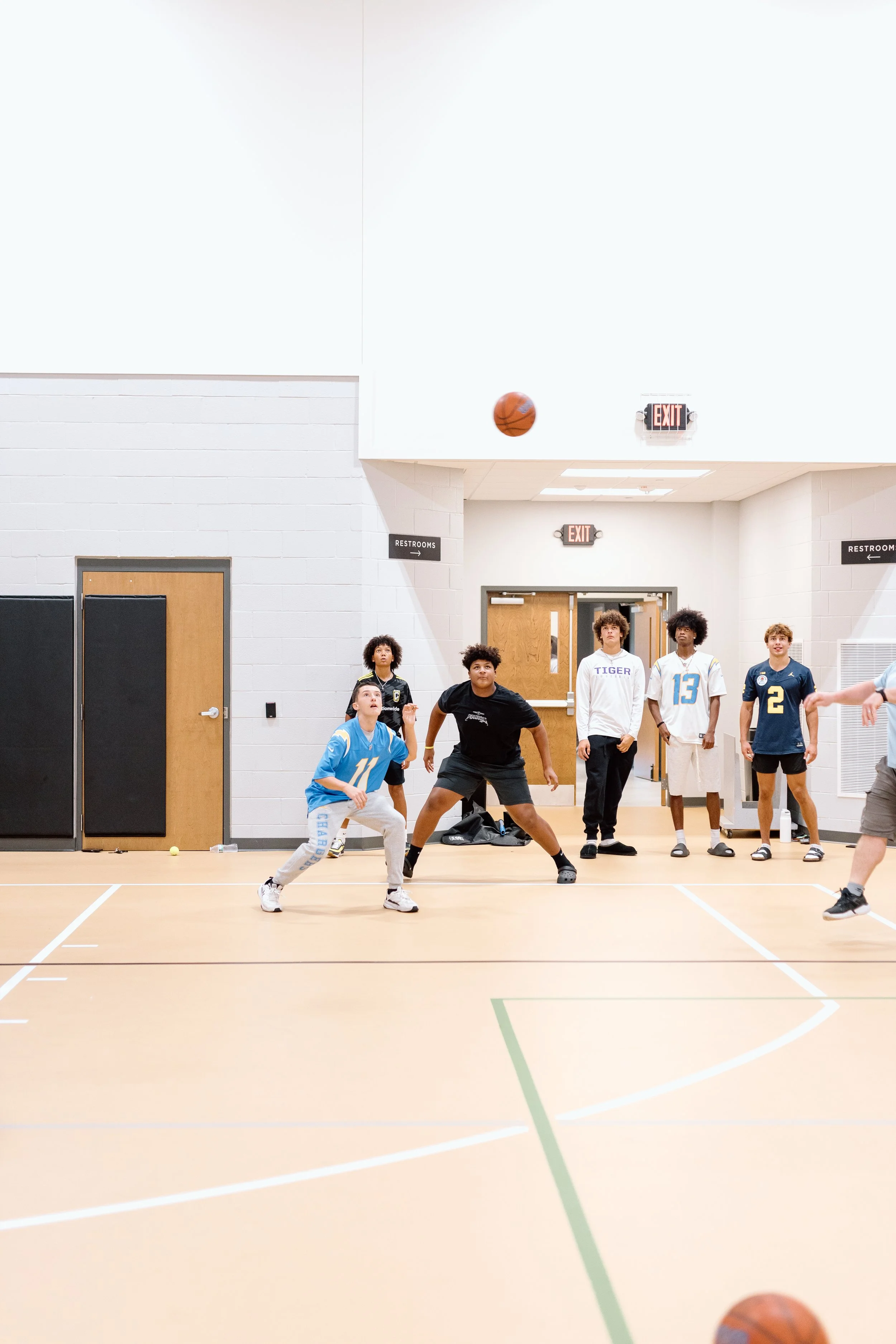 A group of children playing basketball in an indoor gymnasium.