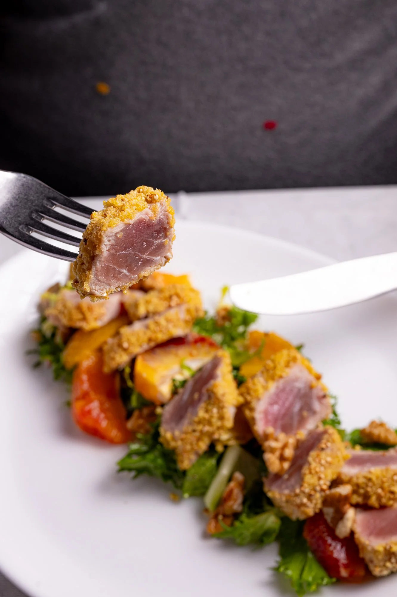 Tonno impanato in crosta di semi di sesamo su un piatto, con insalata.