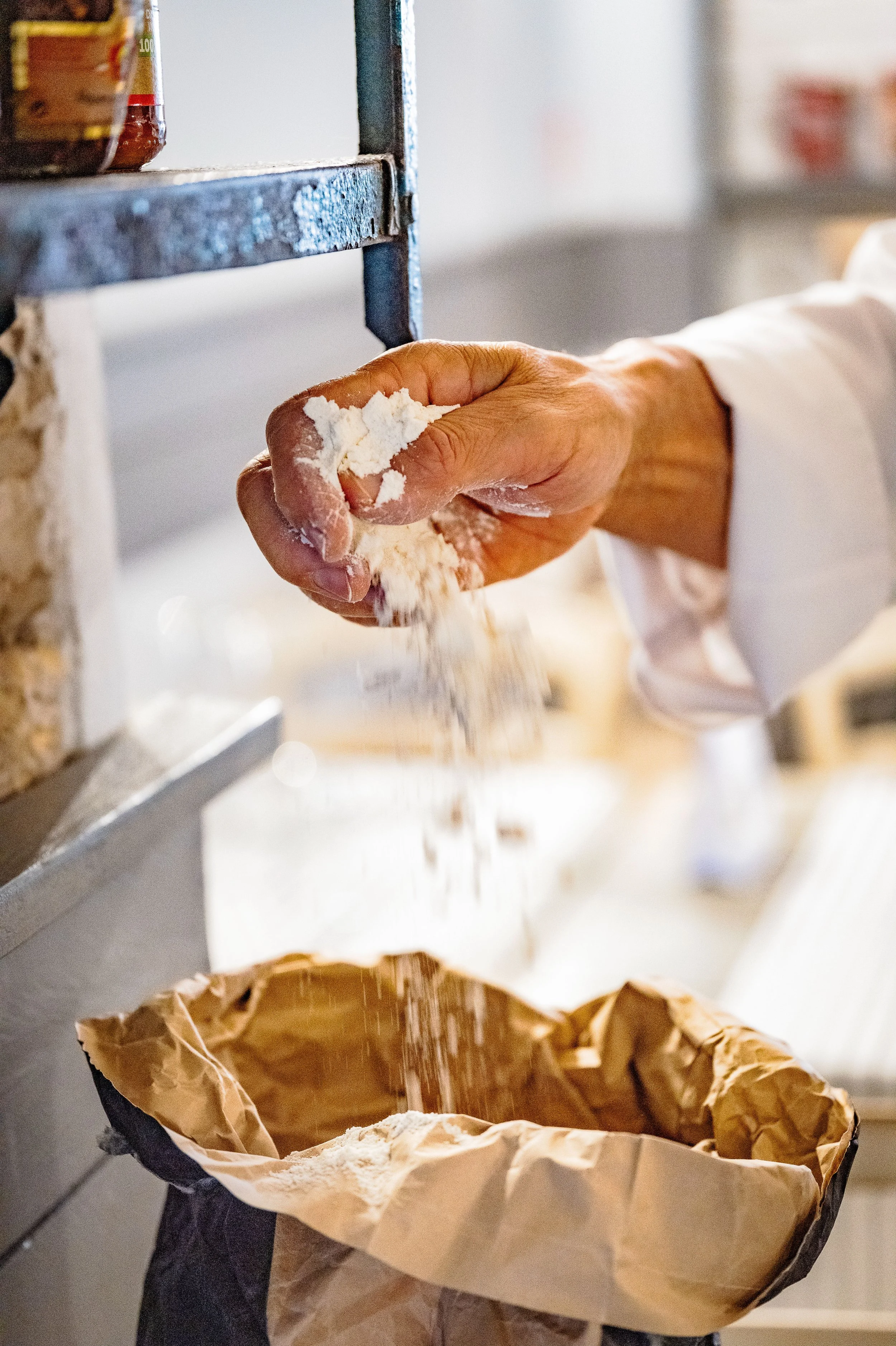 Una mano versa farina dentro un sacco.
