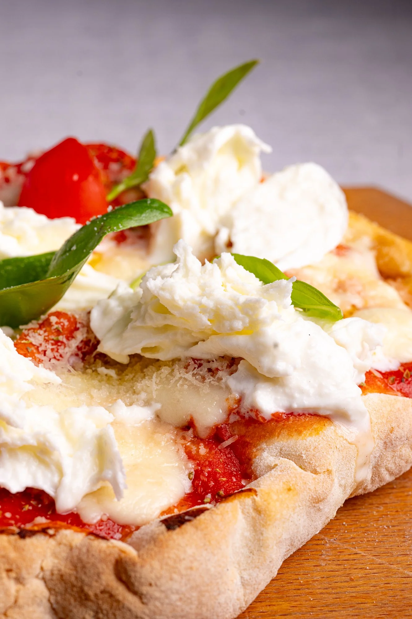 Fetta di pizza con pomodoro, mozzarella, basilico e formaggio grattugiato.