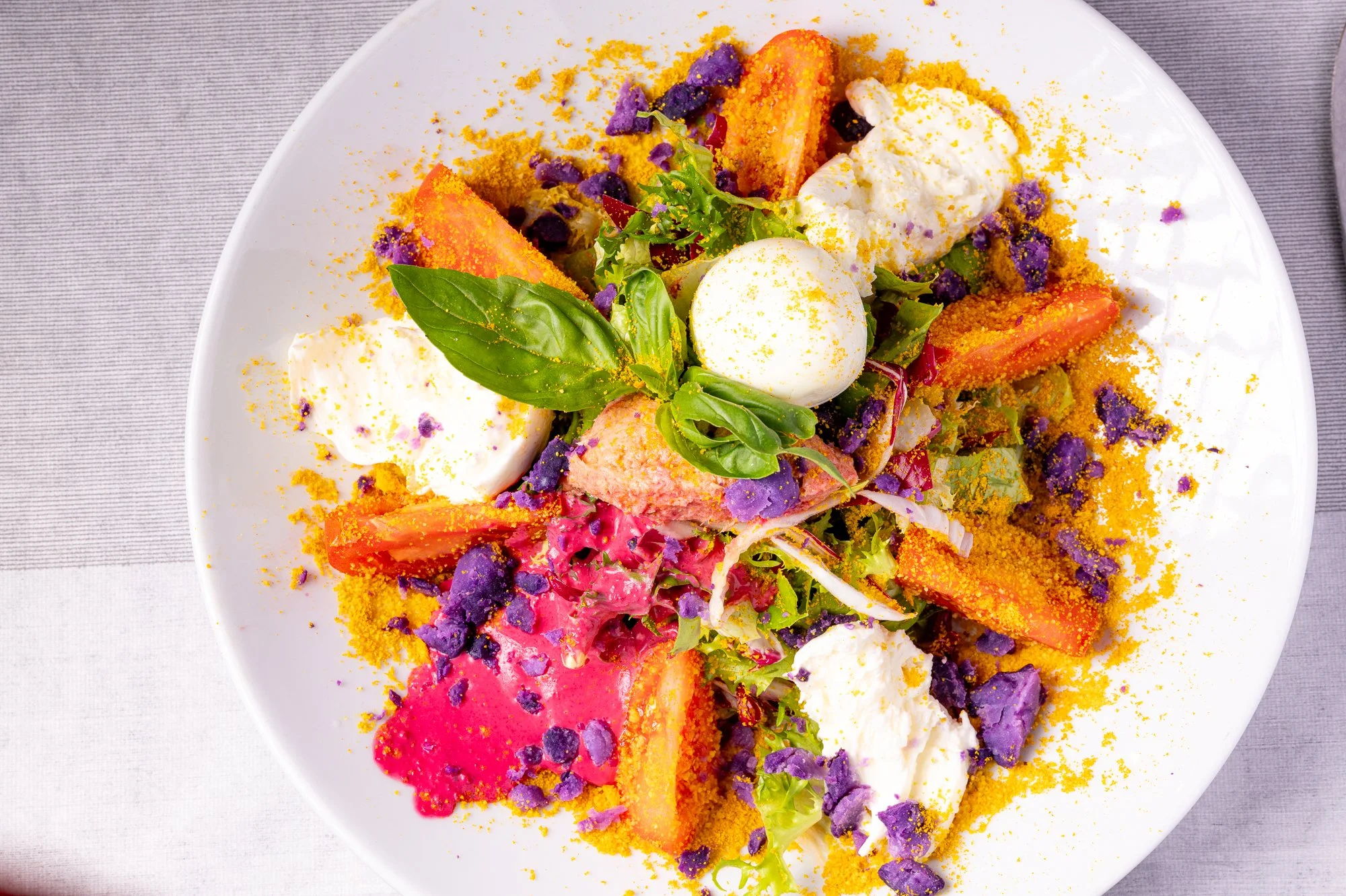 Insalata multicolore con verdure, uova sode, tonno, basilico, patate viola e curcuma.