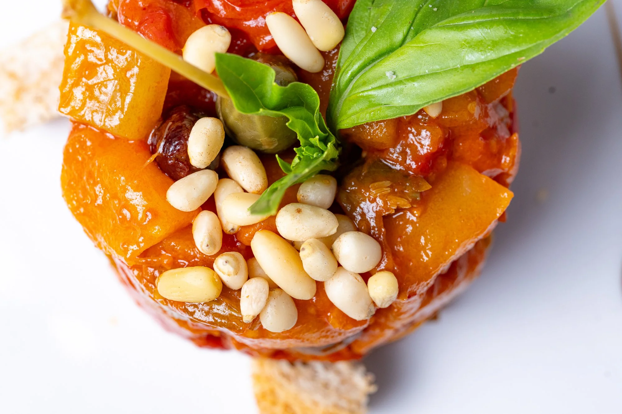 Una caponata di mela decorata con basilico fresco e pinoli.