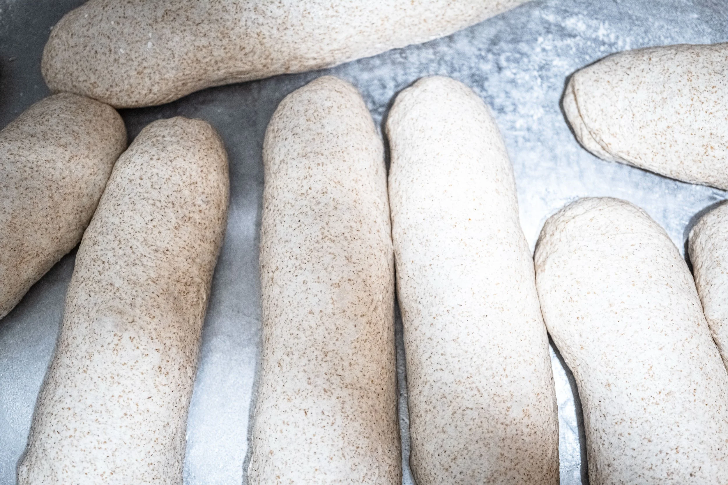 Pane bianco impanato e pronto per essere cotto, disposto su una teglia
