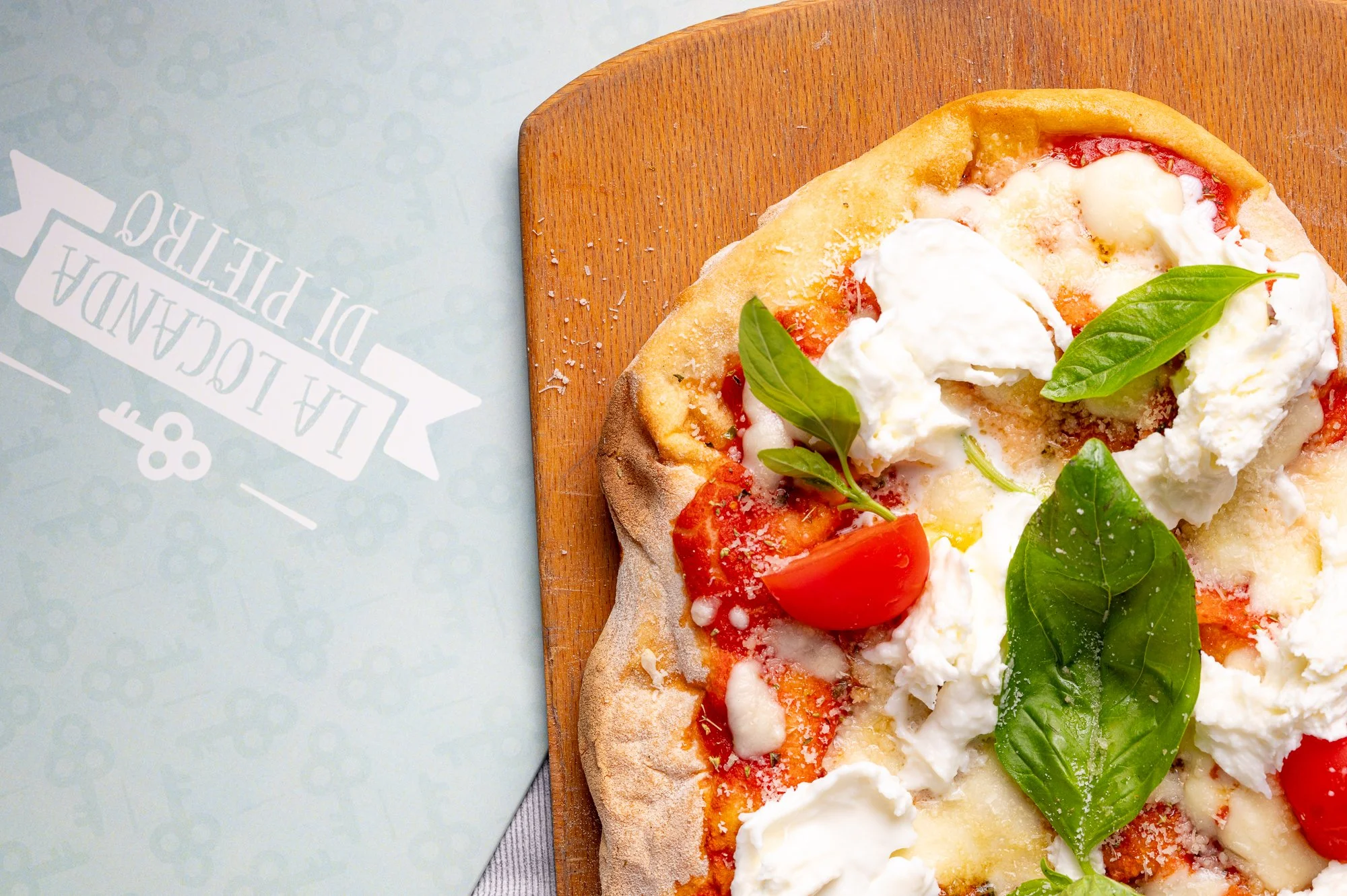 Pizza con pomodoro, mozzarella, basilico fresco e olio d'oliva su un tagliere di legno.