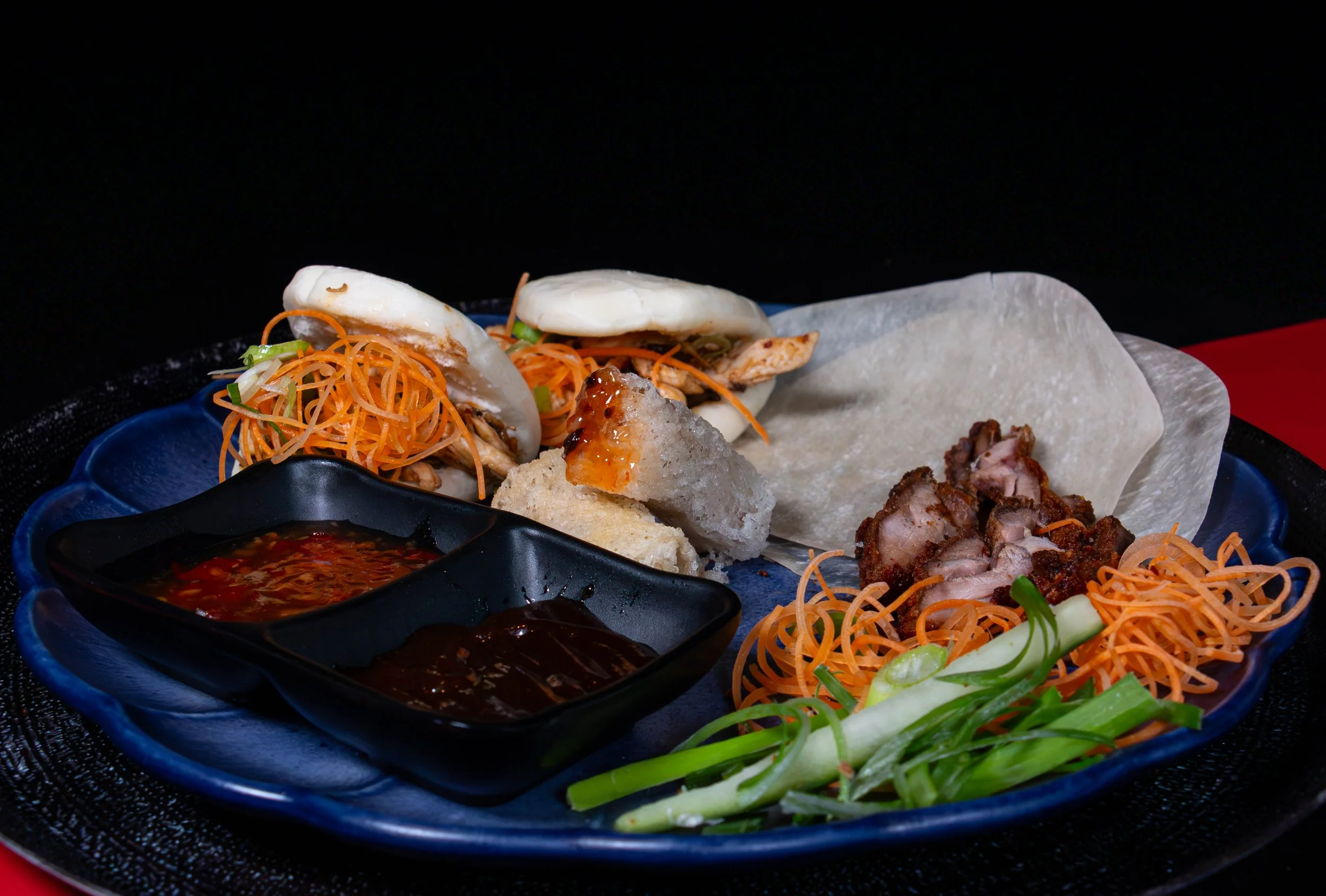 Vietnamese bánh mì met varkensvlees, groenten en saus op een blauw bord