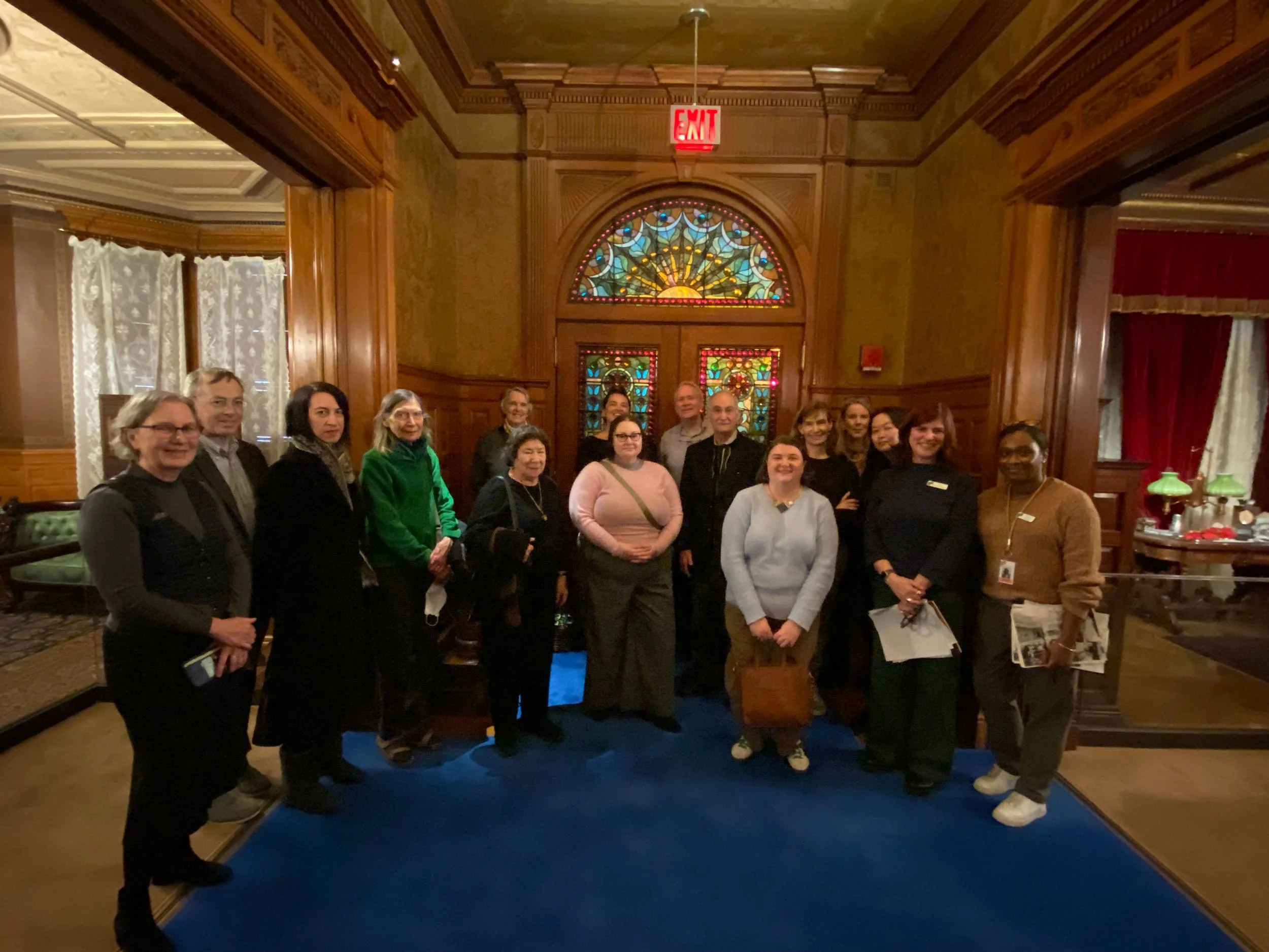A group of people pose for a photo in a large, ornate room with wood details.