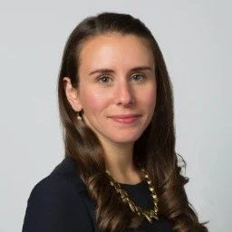 A smiling woman with long dark curly hair
