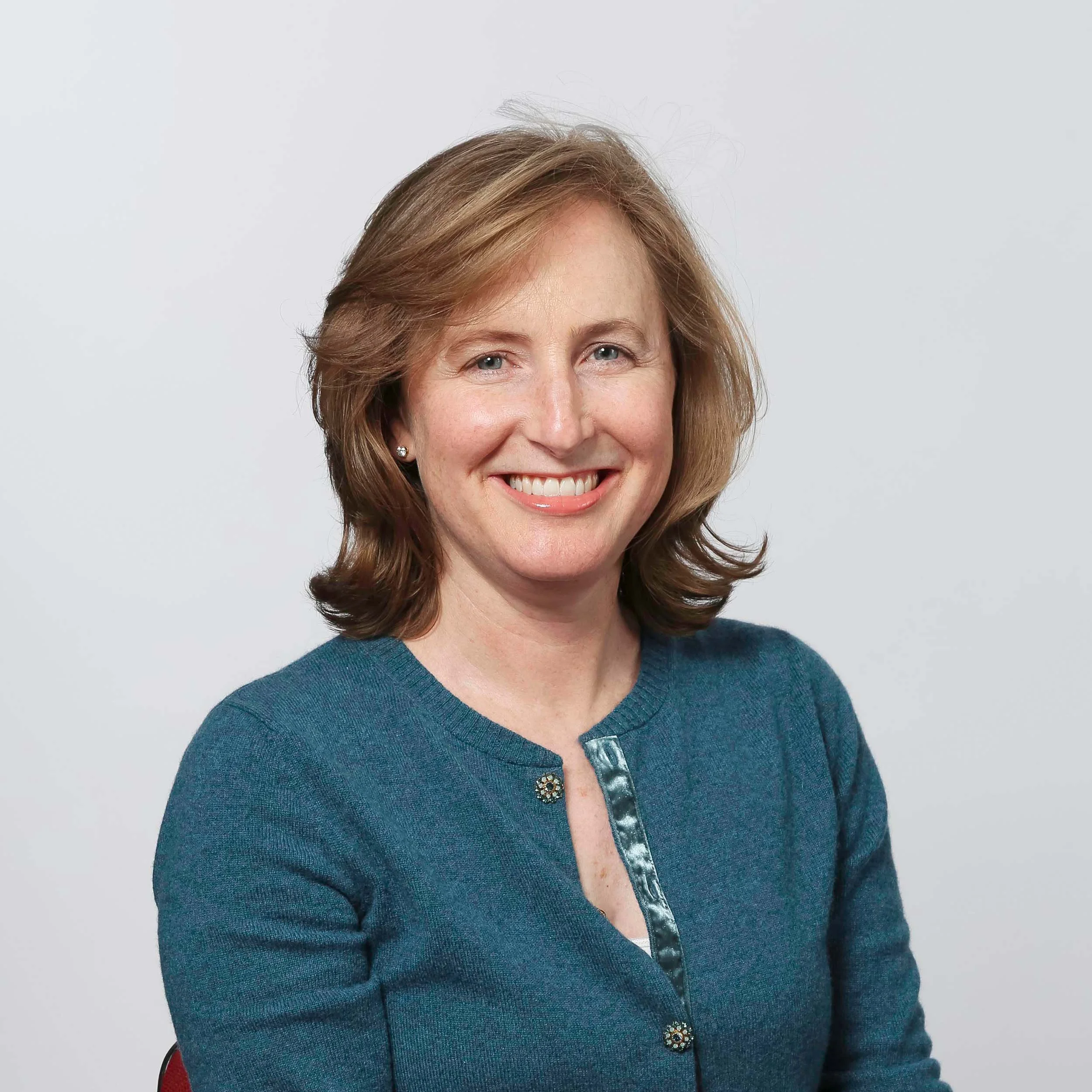A smiling woman in a teal blue top