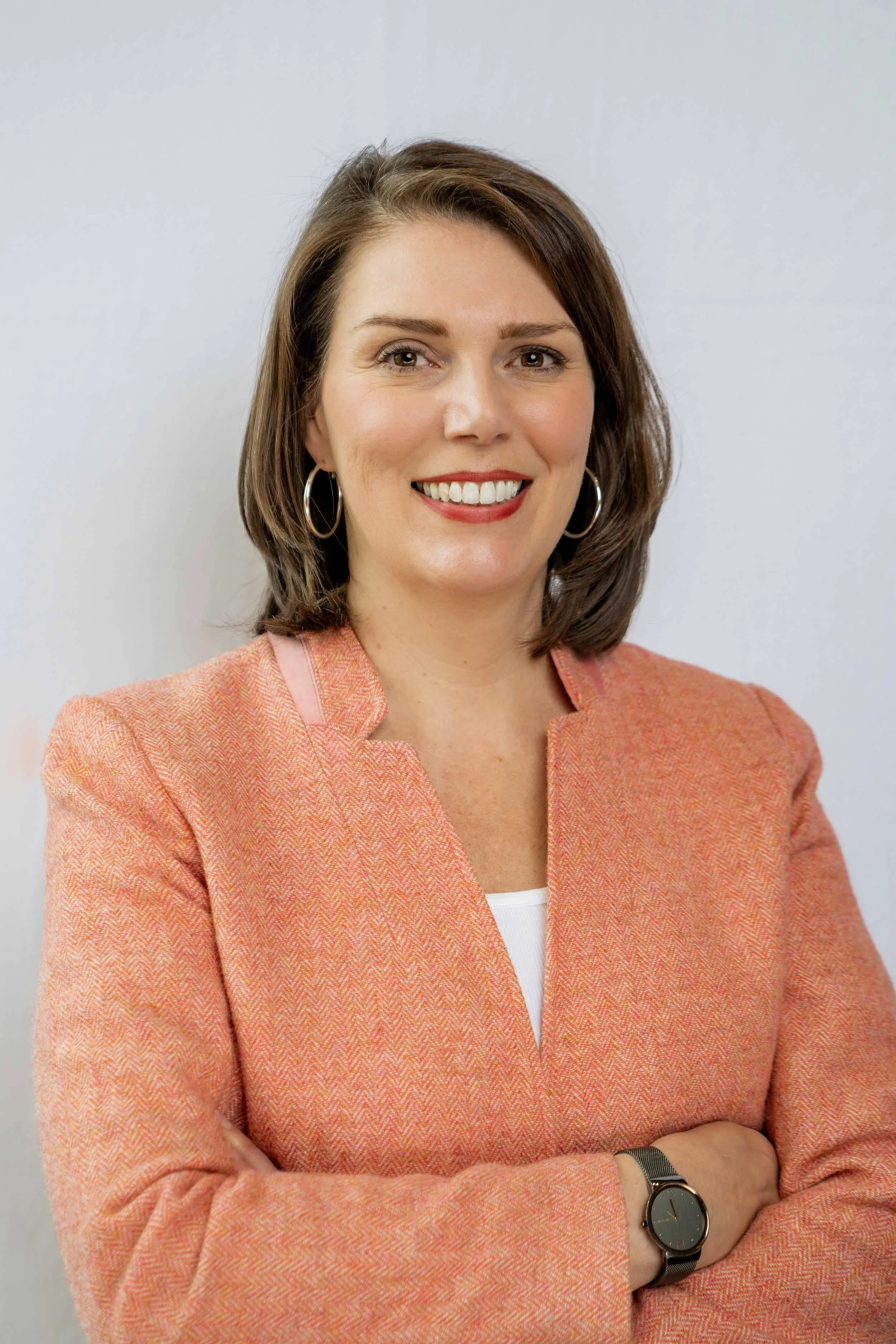 A smiling woman in a peach blazer