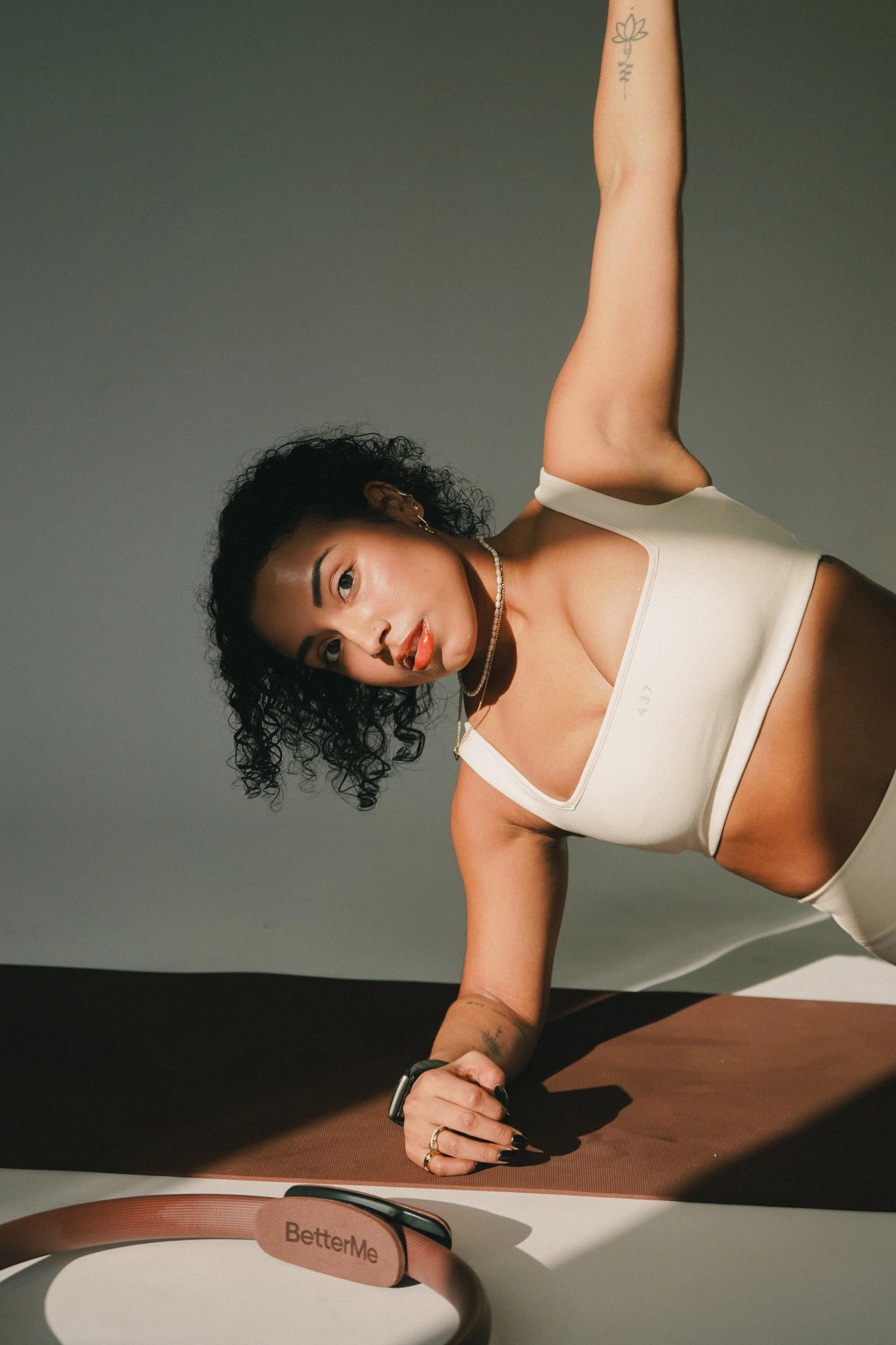 Woman in sportswear doing a plank exercise on a mat, with a fitness tracker and headphones nearby.
