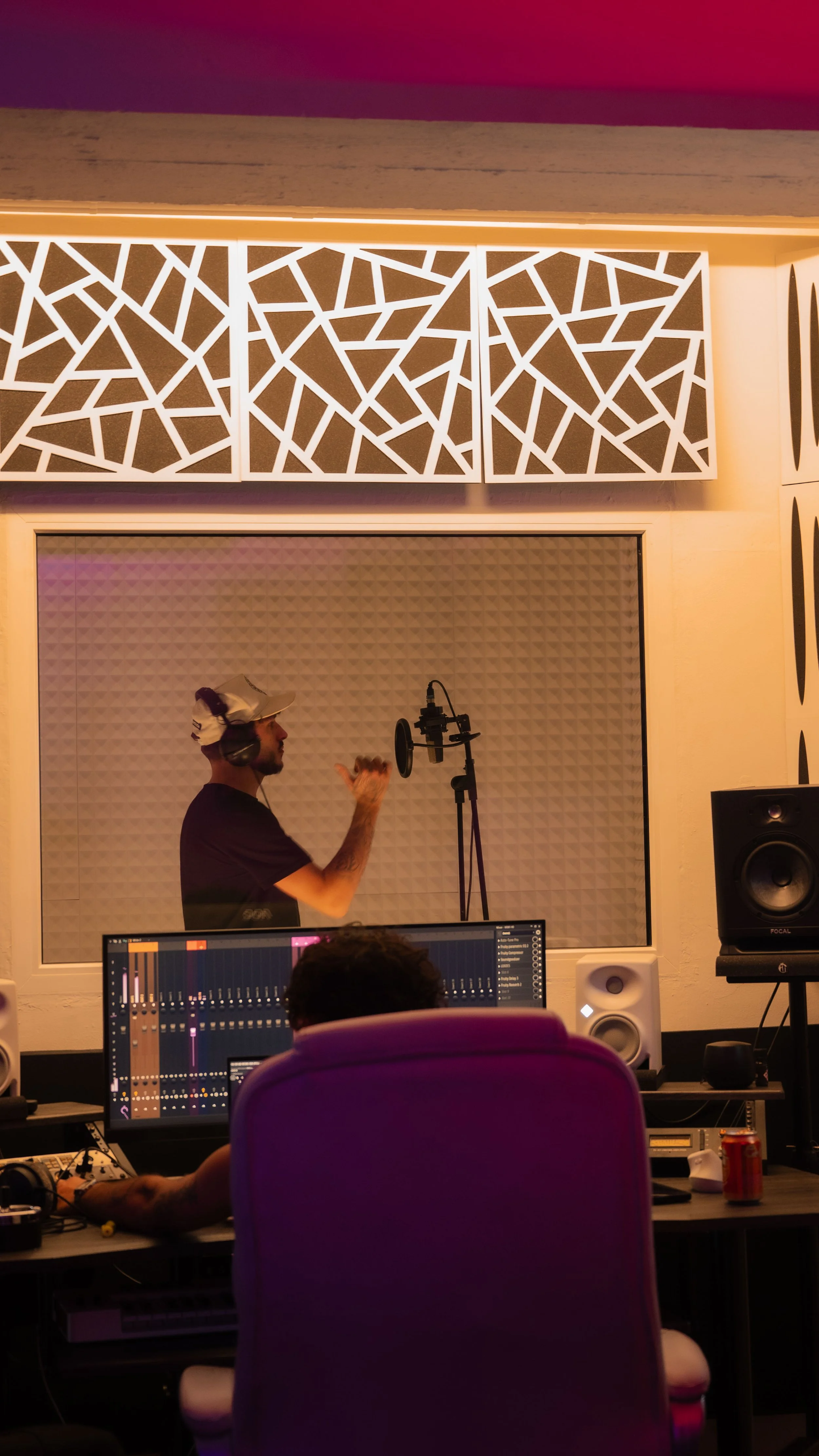 Un homme dans un studio d'enregistrement en train de chanter ou de faire un enregistrement vocal, portant des écouteurs, avec un microscope de studio à proximité.