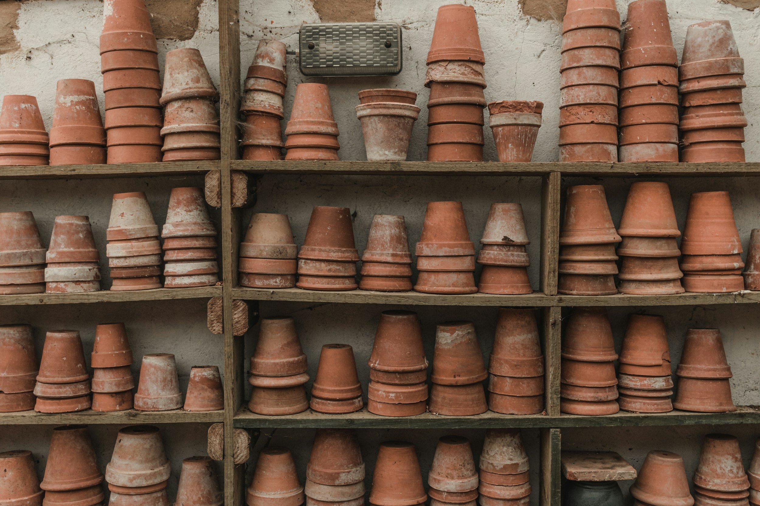 Stacks of terracotta flower pots on a shelf.