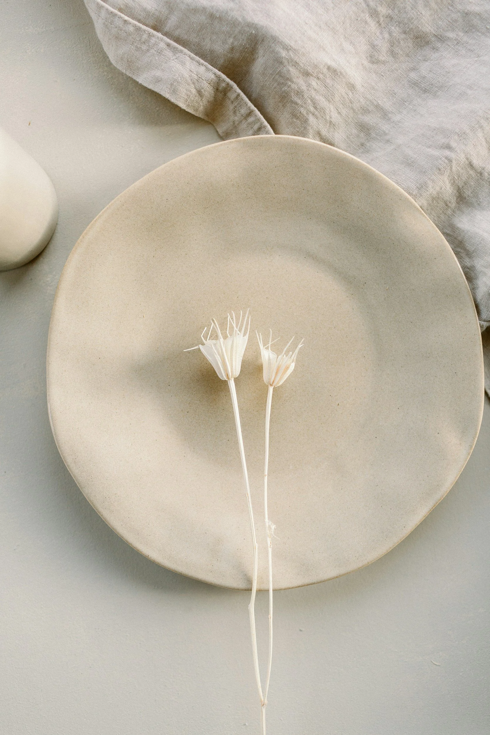 Handmade plate with two long flower stems in the middle.