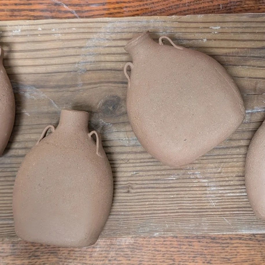 Top-level view of two unfired flasks with a wood board background