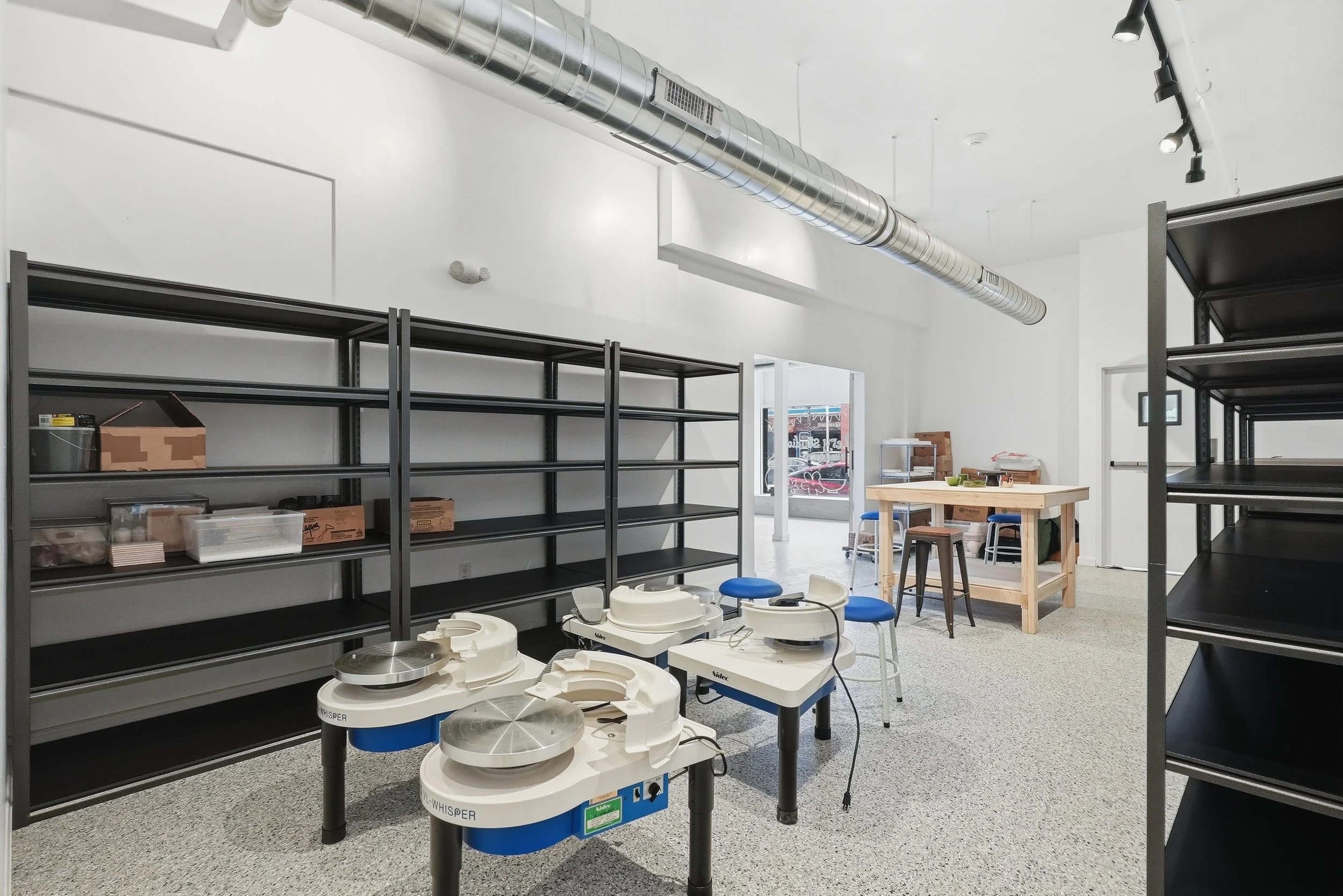 Pottery membership room with 4 wheels, hand building table and shelves