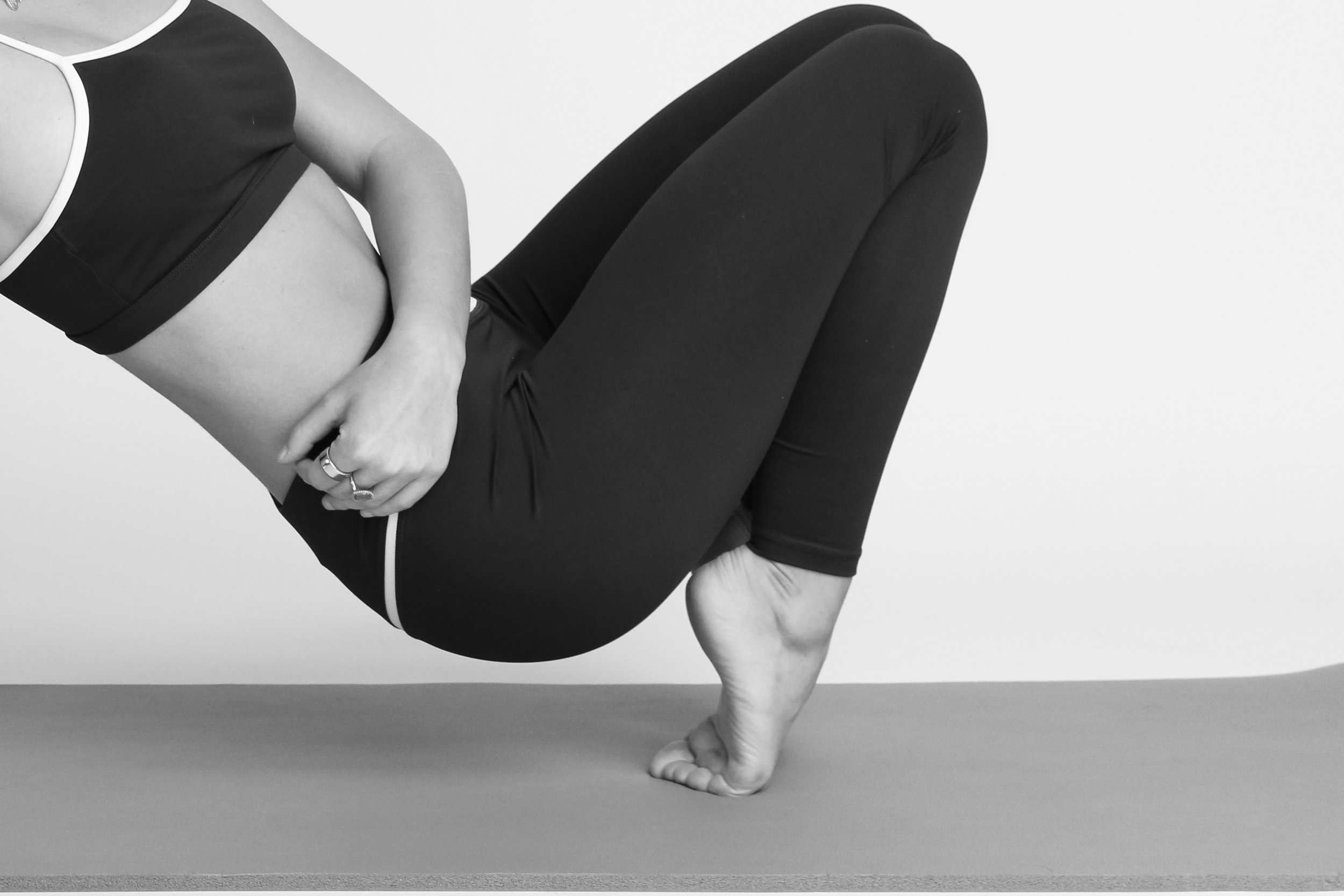 A person performing a yoga pose on a mat, balancing on their right hand with their body raised and legs bent.