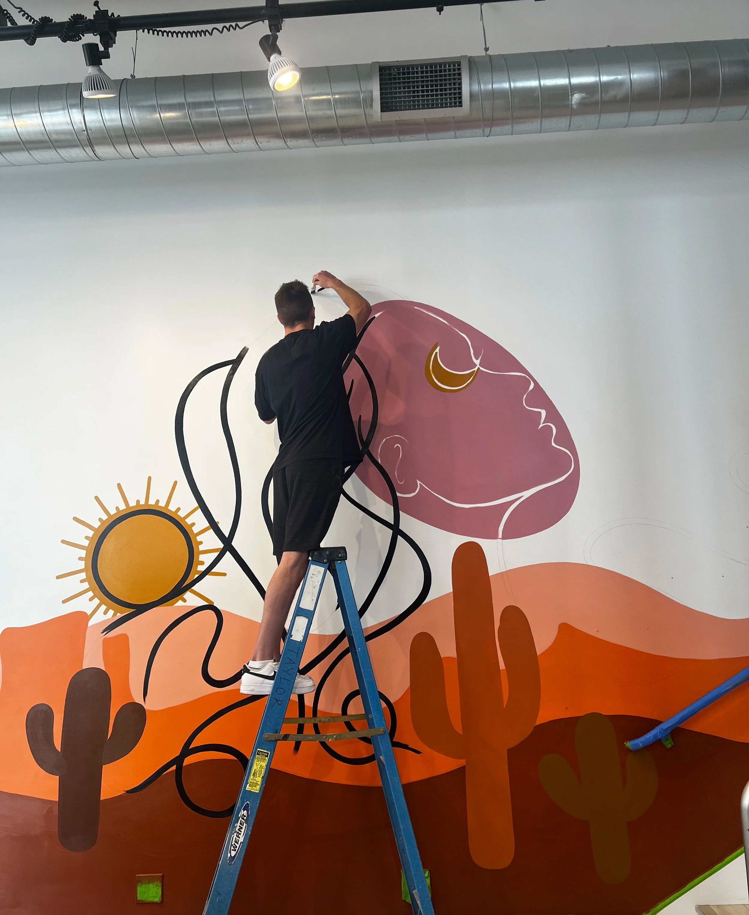 Large-scale mural in progress by Zach Slavin created for a commercial interior space.