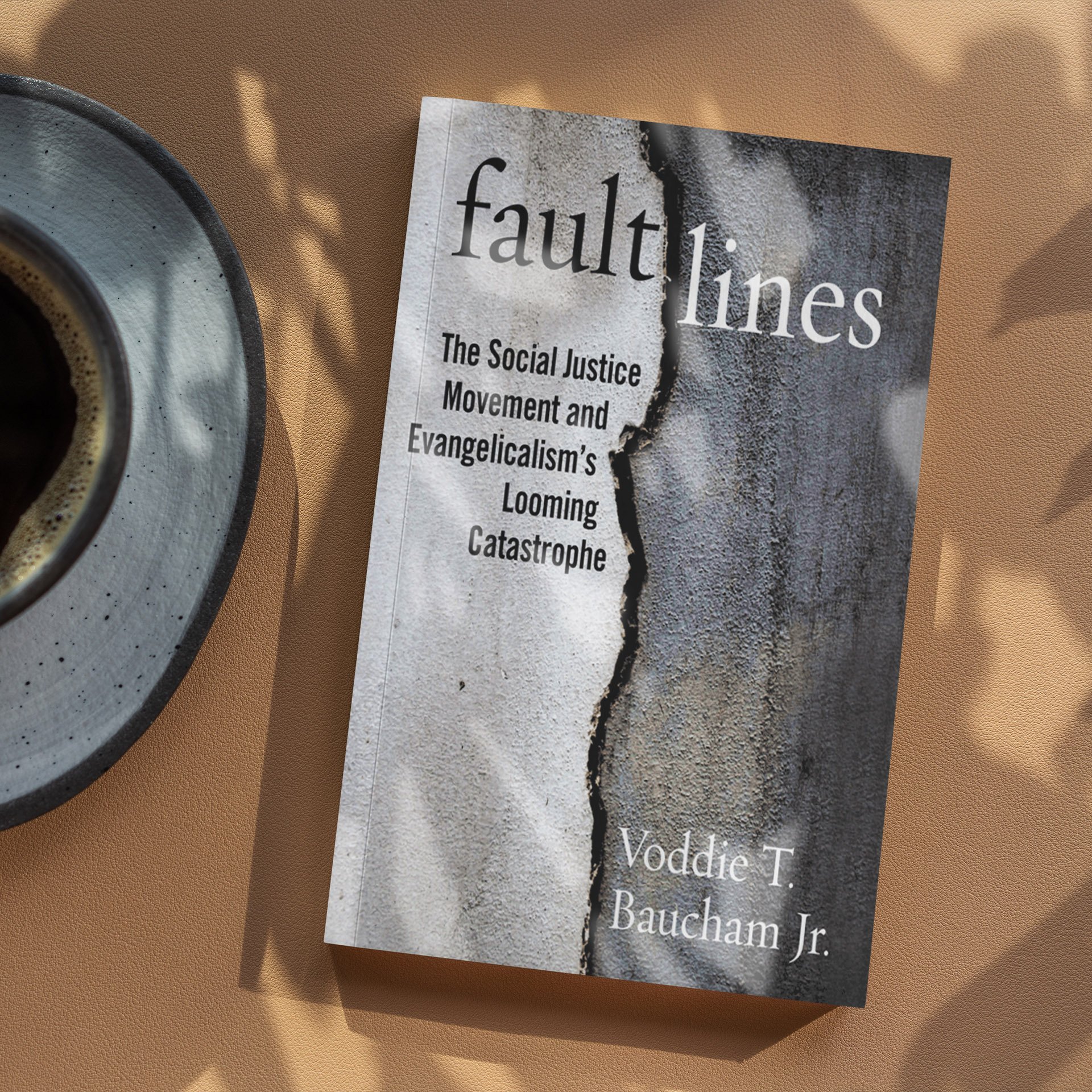 Close-up of a book titled 'Fault Lines' on a table next to a cup of coffee, with the book cover showing a cracked wall.