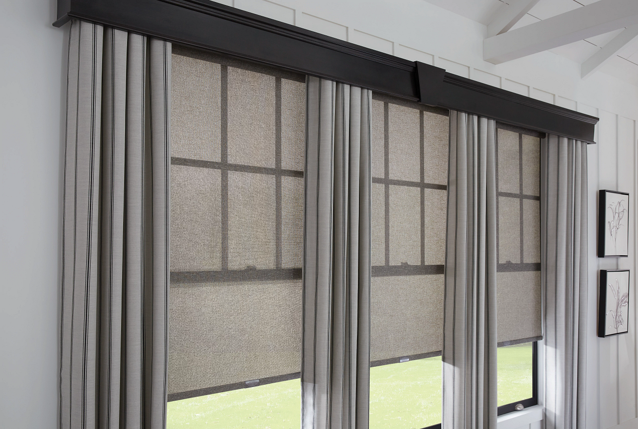 Interior view of a window with blackout roller shades and curtains in a modern room.