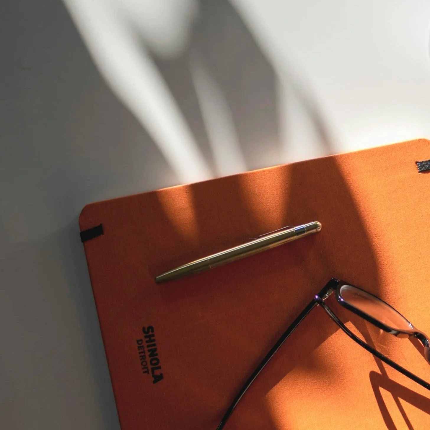 Notebook, pen, and glasses on a desk in soft natural light