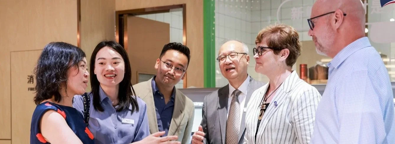 Six people engaged in conversation at an indoor event, with diverse ages and appearances, chatty and smiling.