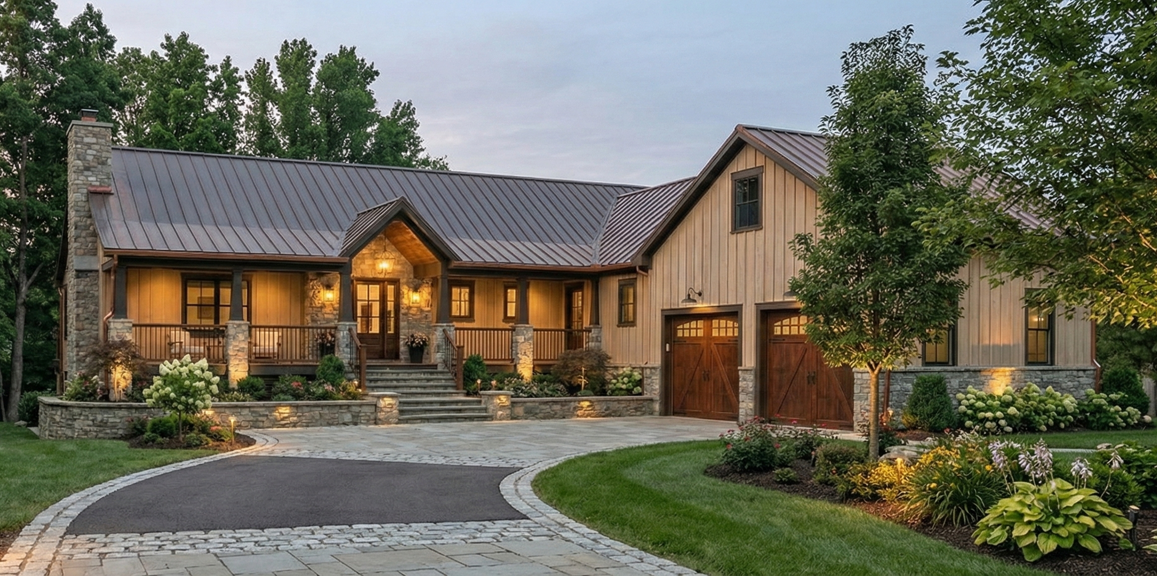 A beautiful two-story house with a stone and wood exterior, porch with stairs, and a double garage, surrounded by landscaped garden and trees, lit by warm outdoor lighting.
